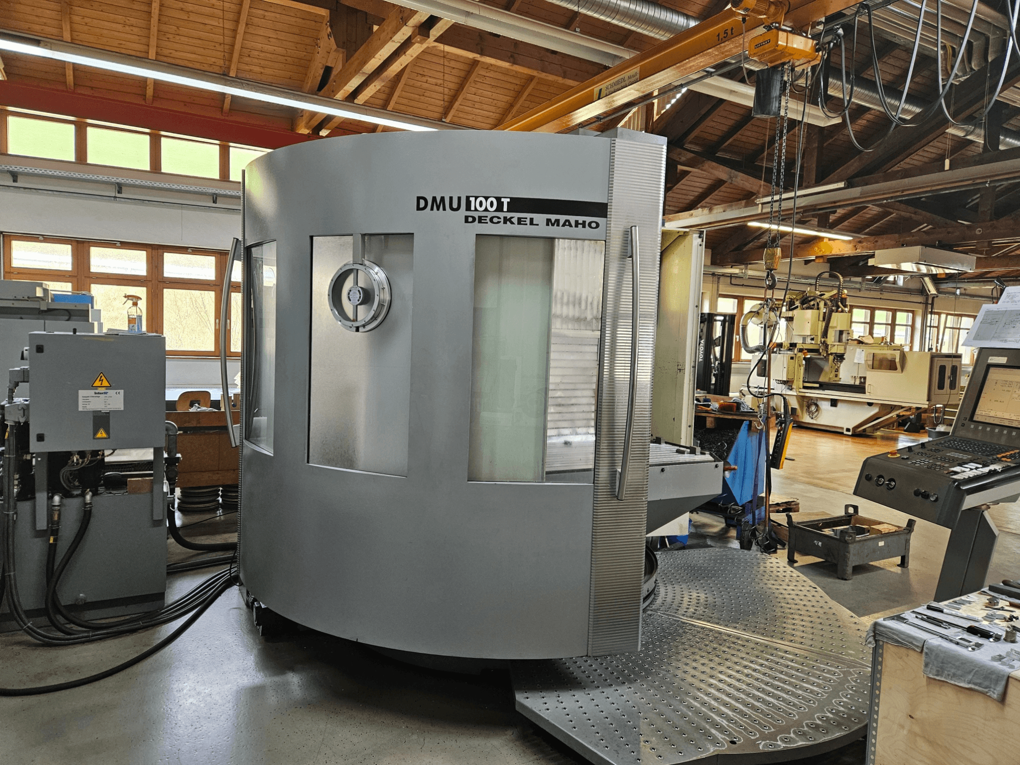 CNC-Maschine DMU 100 T Deckel Maho in der Frontansicht mit großer runder Basis, Bedienfeld und Glasgehäuse.