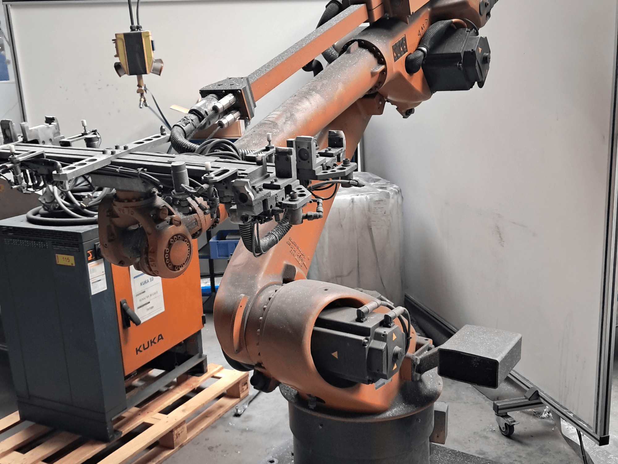KUKA KR 30L16-2-Roboterarm in Seitenansicht mit komplexem Endeffektor und Steuerkabeln, daneben eine KUKA-Steuerbox.