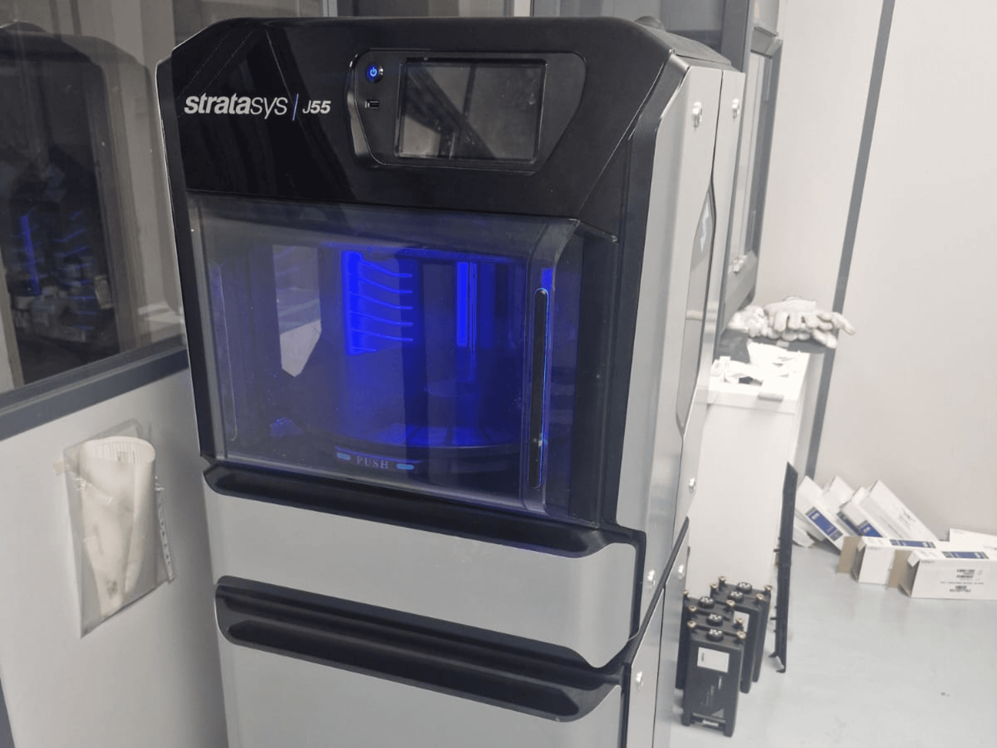Stratasys J55 Prime Kunststoff-3D-Drucker in einer Seitenansicht, die das schlanke Design und den beleuchteten Druckbereich zeigt.