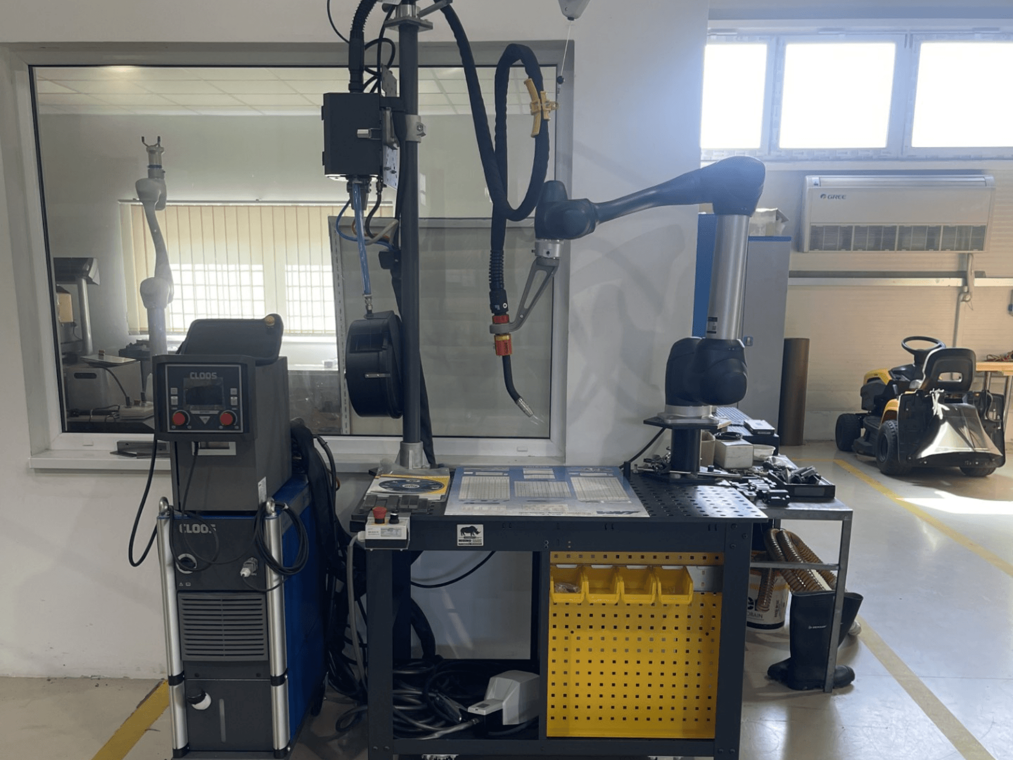 Kollaborationsroboter DOOSAN M1013 in einer Werkstatt, Seitenansicht mit Schweißausrüstung und Werkzeugen auf einer Werkbank.