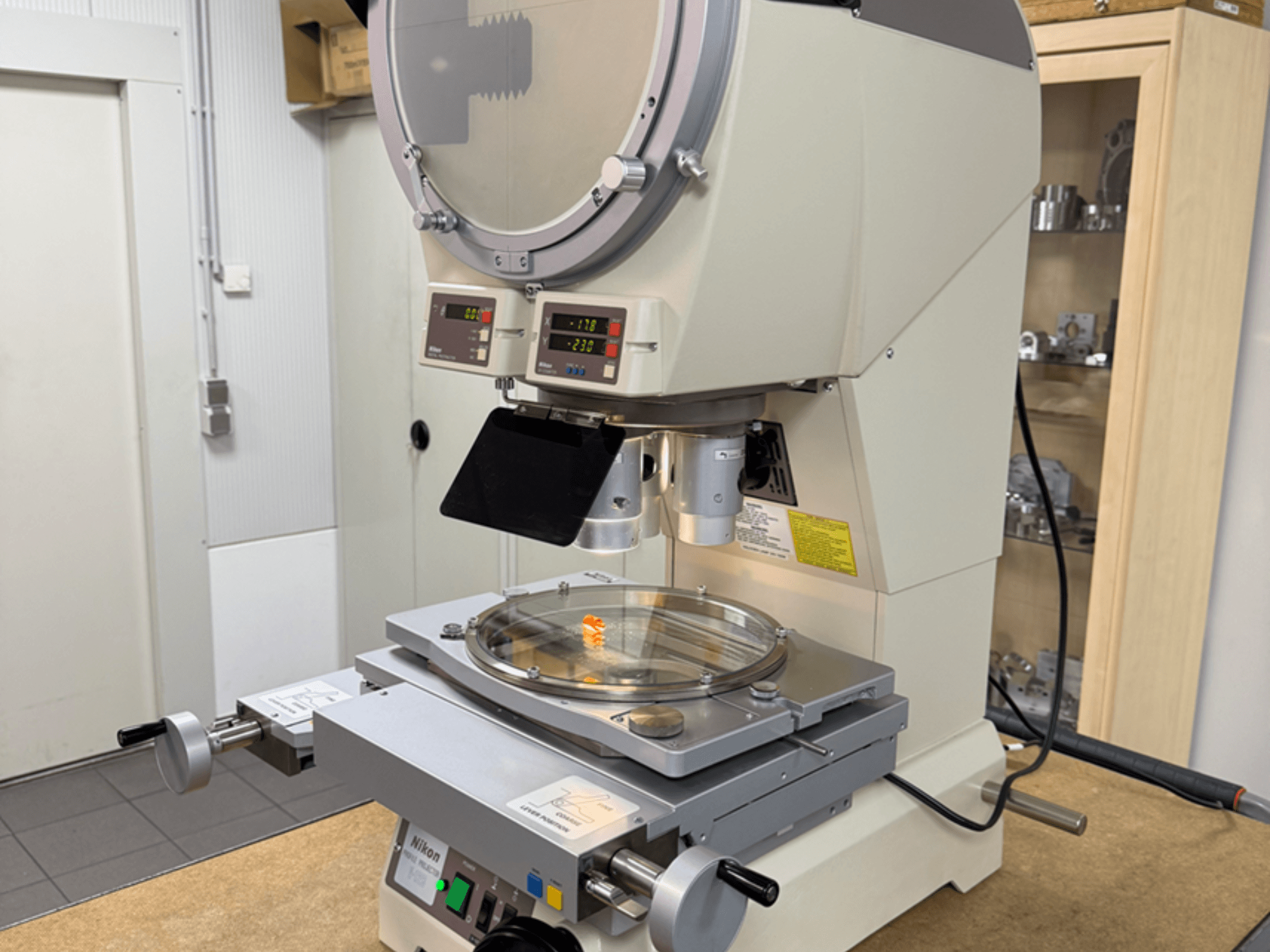 Nikon-Mikroskopmodell in der Vorderansicht, mit digitalen Anzeigen, verstellbarem Tisch und kreisförmiger Glasplatte.