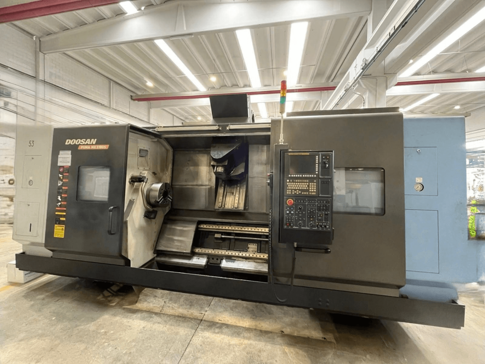 Vorderansicht einer DOOSAN PUMA MX3100-Horizontal-Drehmaschine mit Bedienfeld und sichtbarem Spindel- und Werkzeughalterbereich.