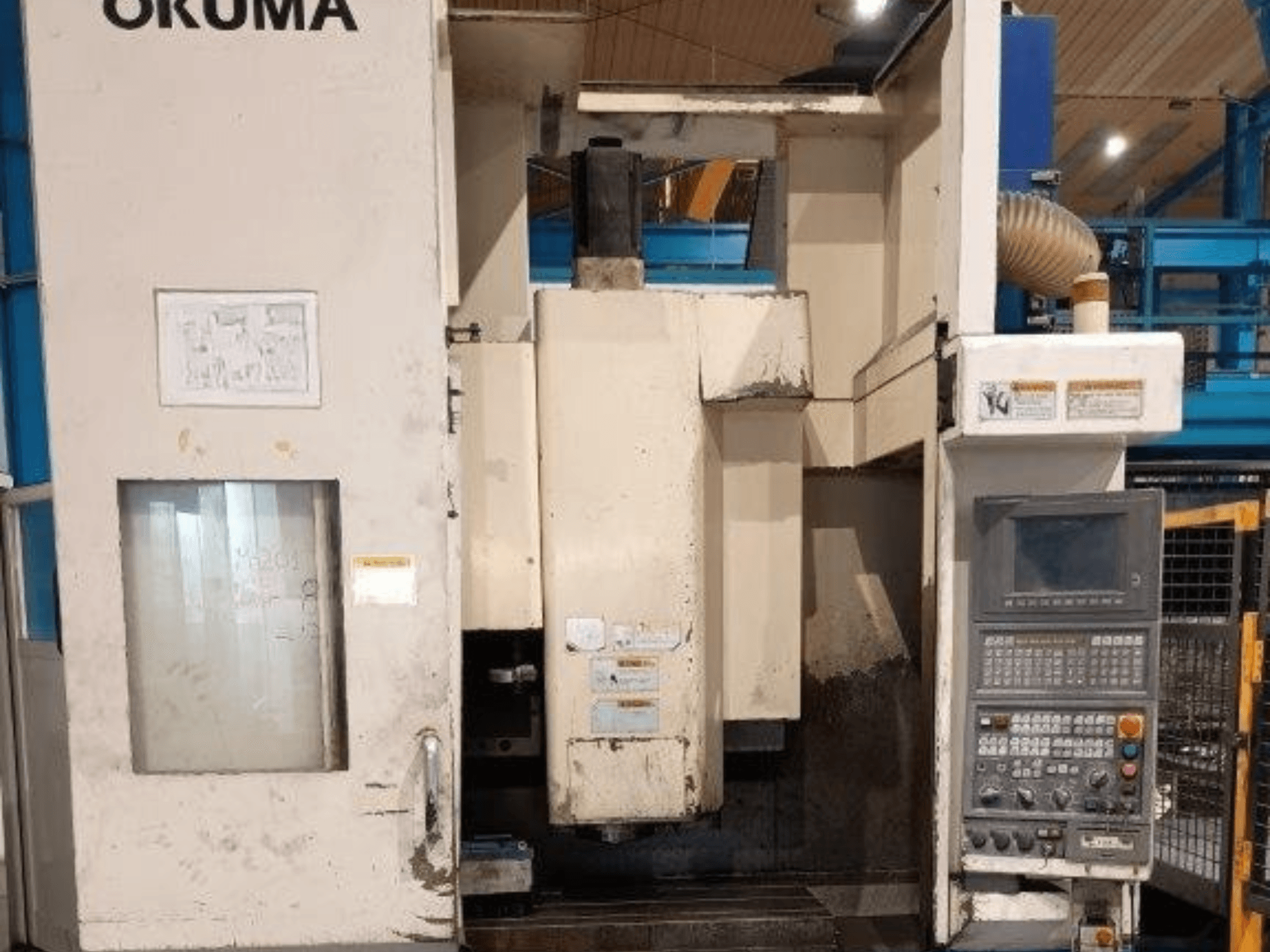 Okuma CNC-Fräsmaschine, Vorderansicht, mit Bedienfeld mit Tasten, Display und sichtbaren Markierungen auf dem Maschinenkörper.