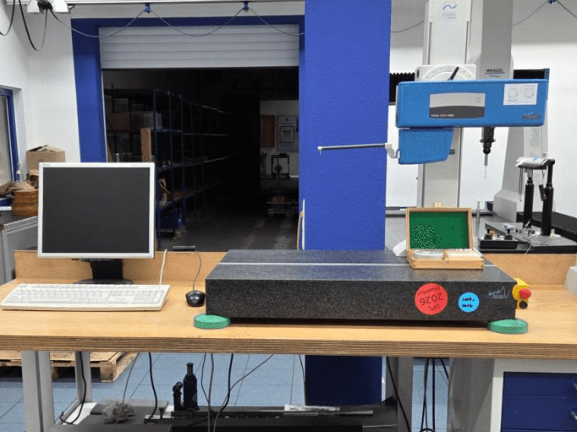 KMG JENOPTIK wave C8000 in einer Werkstatt mit Monitor, Tastatur und Granitmessfläche. Ansicht von vorne.