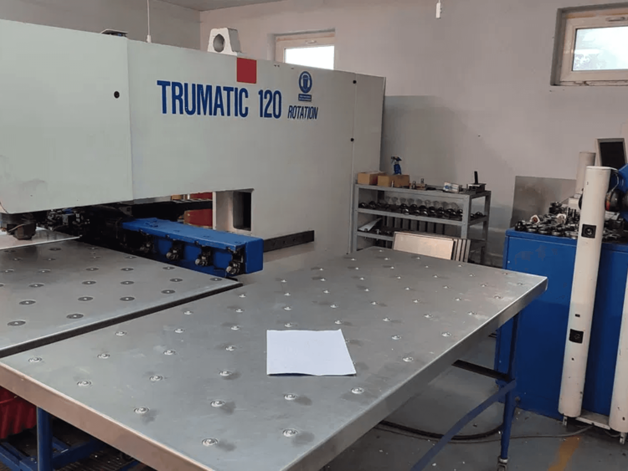 TRUMPF TRUMATIC 120R CNC-Stanzmaschine in der Vorderansicht mit Metalltisch mit Stanzlöchern und Rohblech.