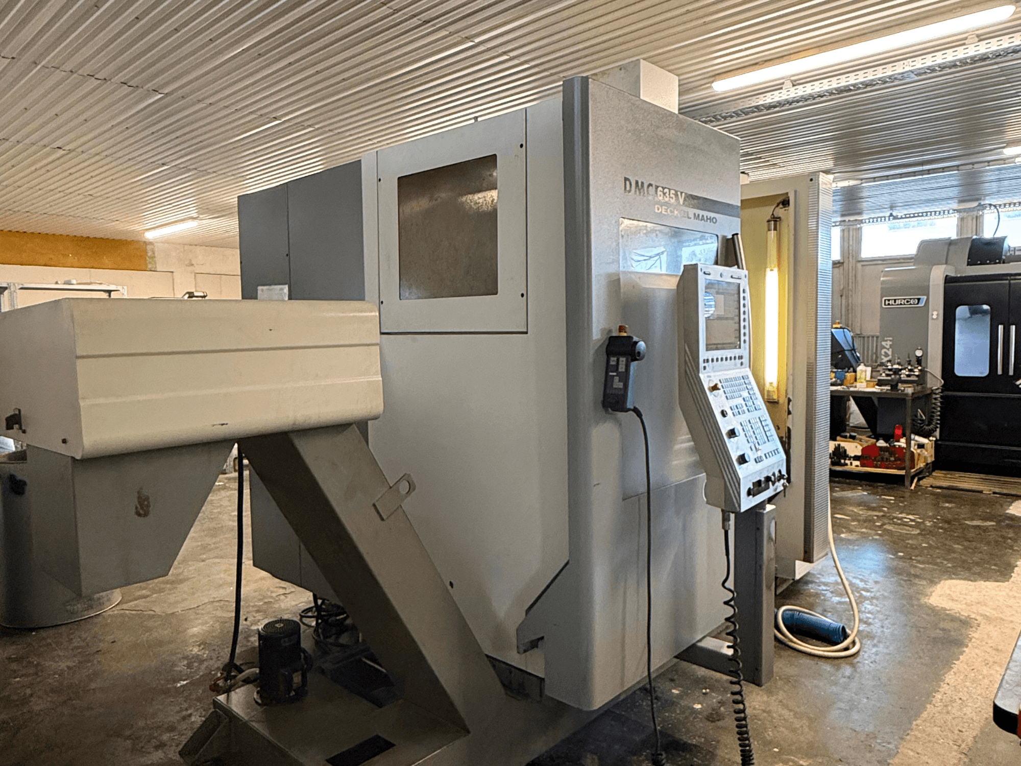 DMC G635V Fräsmaschine in einer Werkstatt, Vorderansicht mit Bedienfeld und angeschlossenen Elektrowerkzeugen.