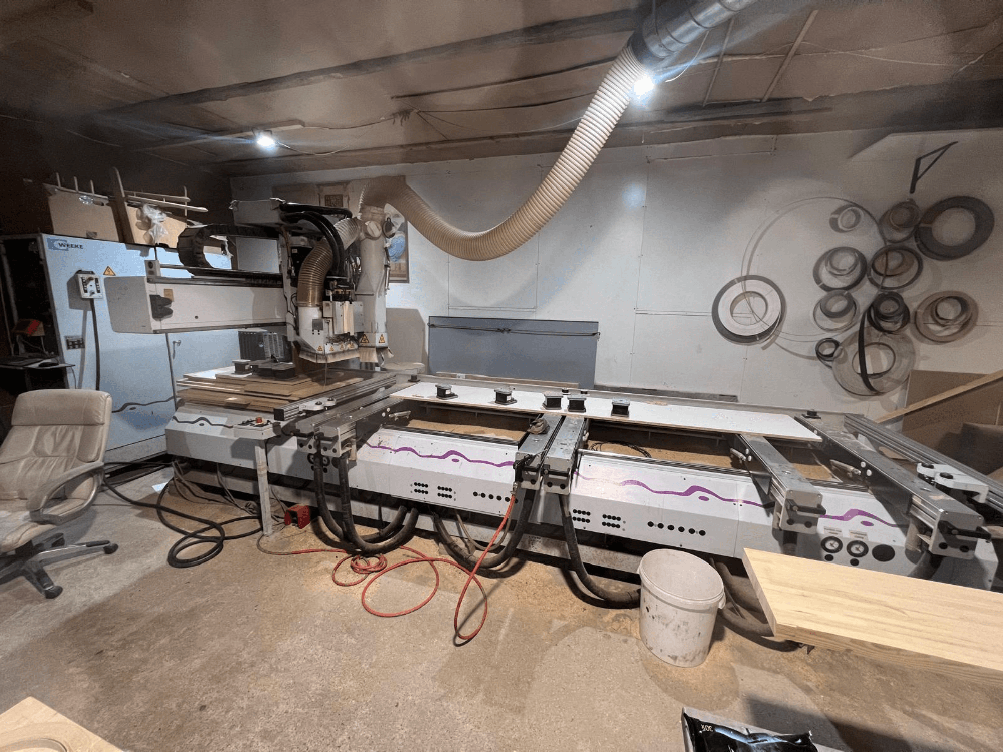 CNC-Holzbearbeitungszentrum Weeke OPTIMAT BP 120 in der Werkstatt, Vorderansicht mit auf der Arbeitsfläche sichtbaren Holzstücken und Werkzeugen.