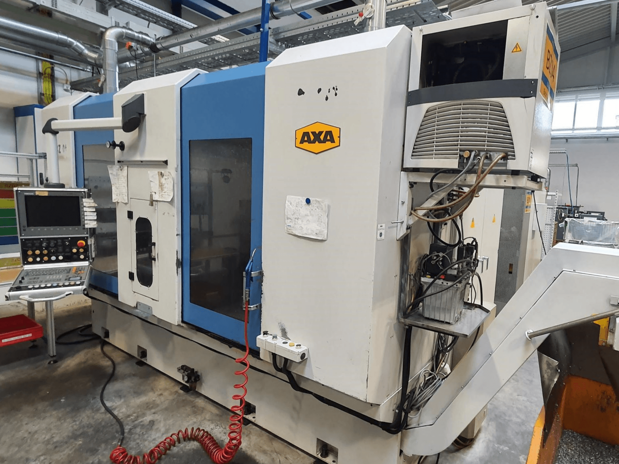 Vertikales Bearbeitungszentrum AXA DBZ, Vorderansicht, mit Bedienfeld und sichtbarem Detail des Kühlmittelsystems.