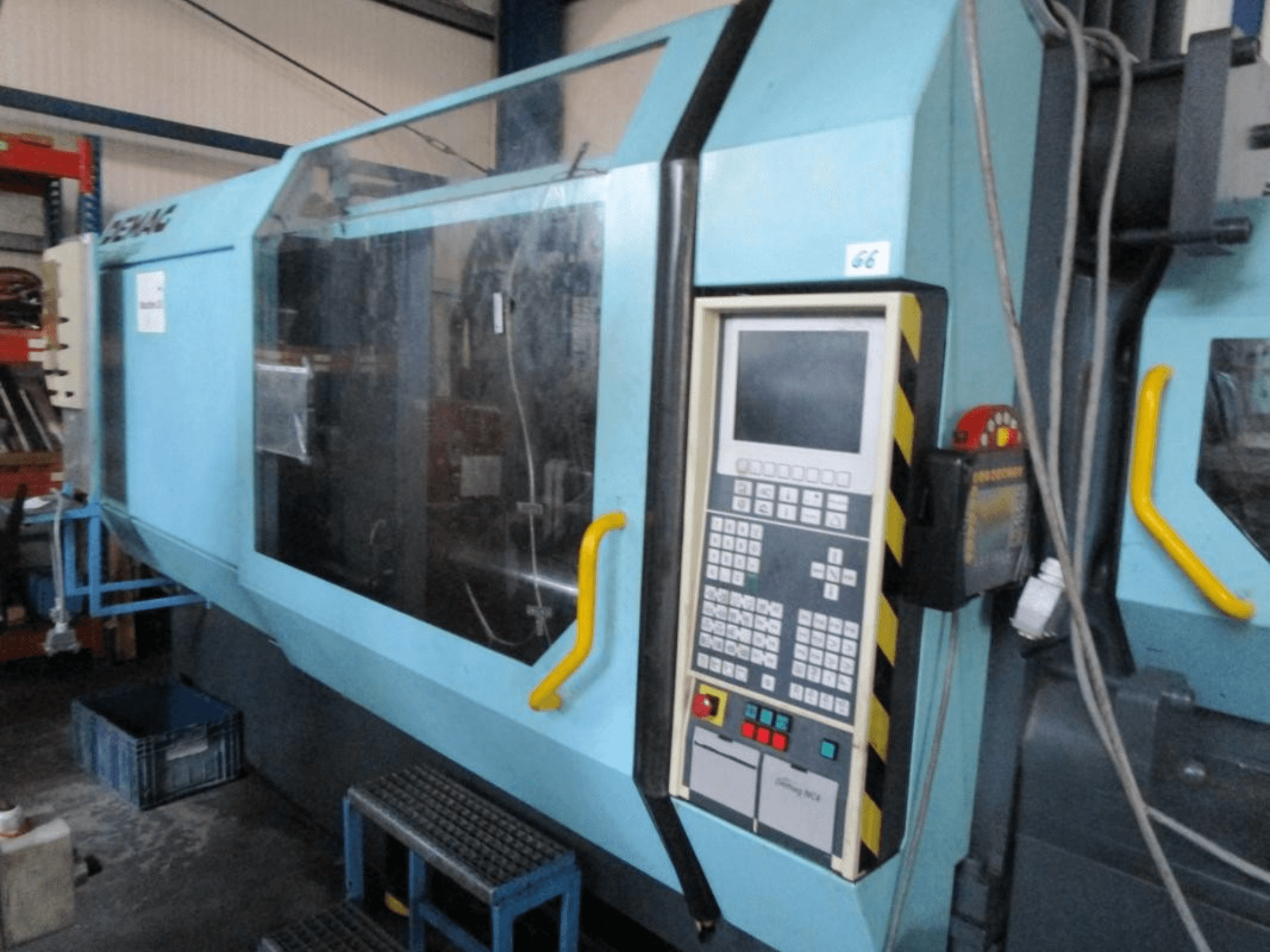 Demag Erdotech 500-3300 hydraulische Spritzgießmaschine, Vorderansicht, mit Bedienpult und durchsichtiger Sicherheitsabdeckung.