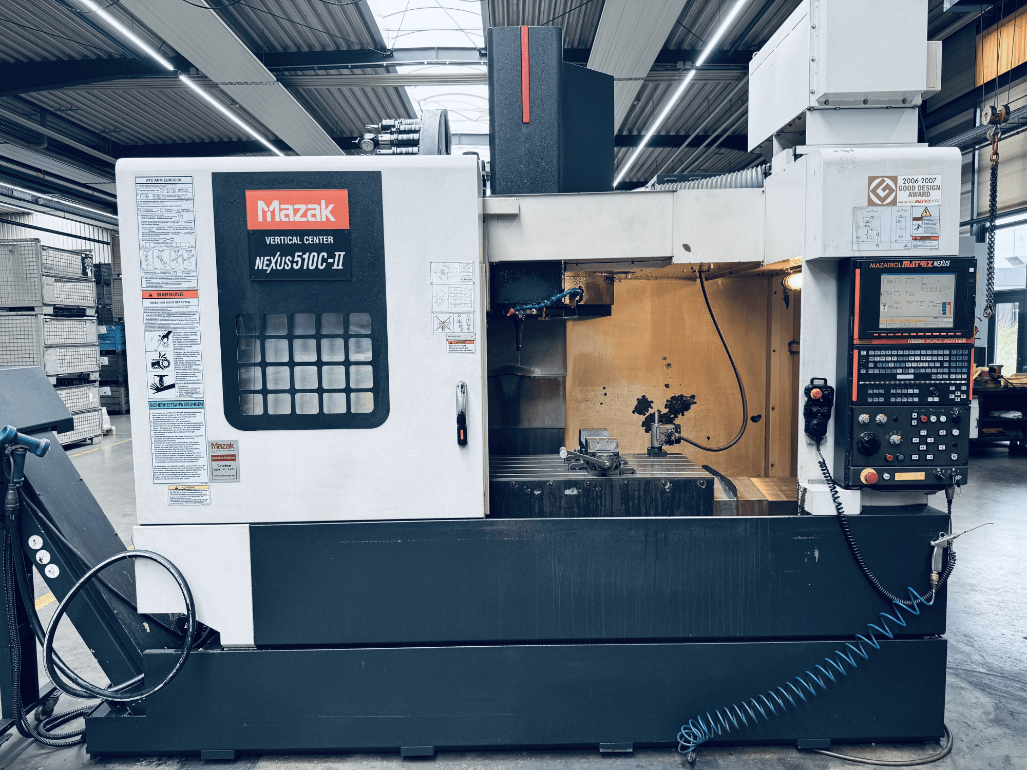 Mazak Vertikalbearbeitungszentrum Nexus 510C-II, Vorderansicht, mit Blick auf das Bedienfeld, den Arbeitsbereich und die Betriebsfunktionen in einer Werkstattumgebung.