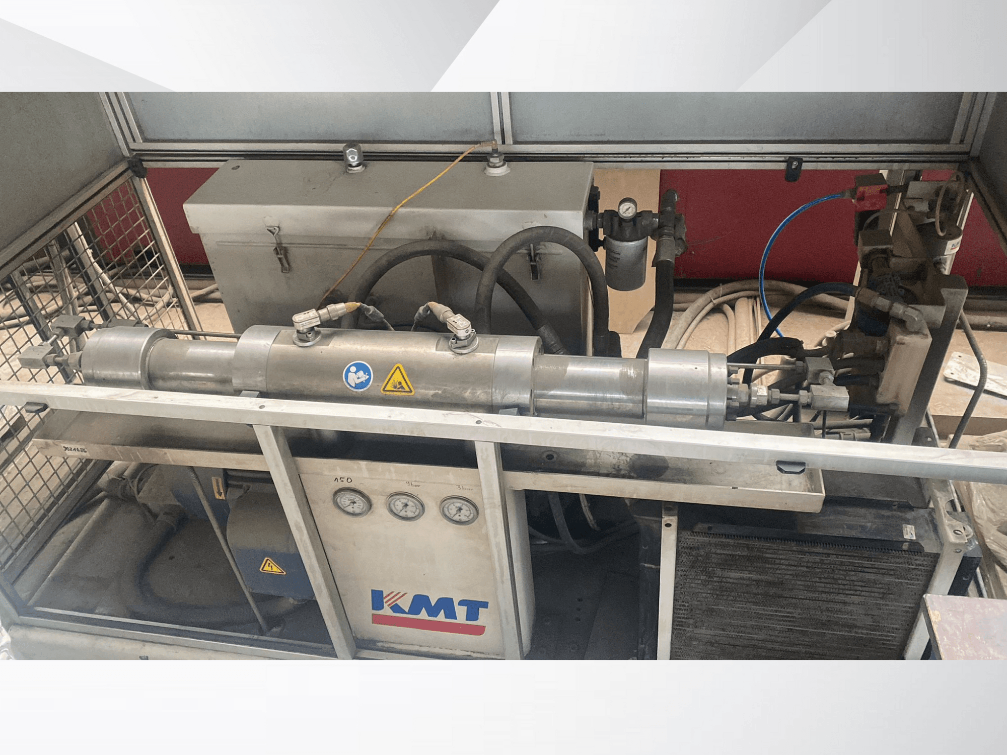 KMT-Hydraulikmaschine in der Vorderansicht, mit Manometern, Schläuchen und Metallgehäuse, ideal für industrielle Anwendungen.