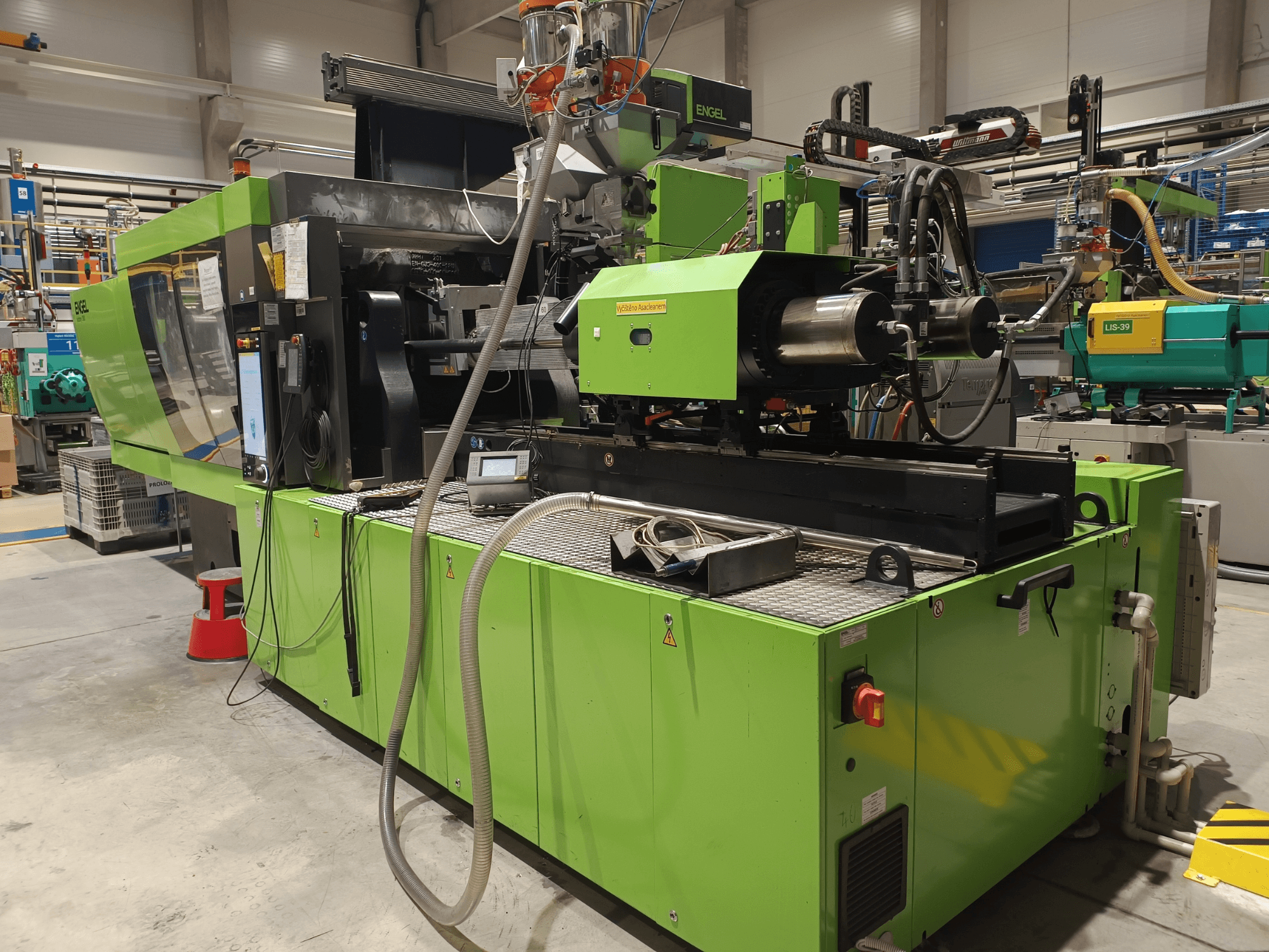 Engel-Spritzgießmaschine, Seitenansicht, grünes Äußeres, mit Touchscreen-Panel und sichtbaren Hydraulikkomponenten.