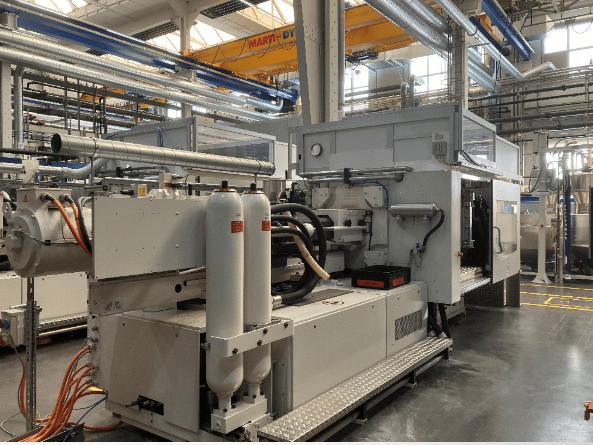 Industriemaschine in Seitenansicht mit mehreren Schläuchen, zwei vertikalen Tanks und Bedienfeld; Marke/Modell nicht sichtbar.