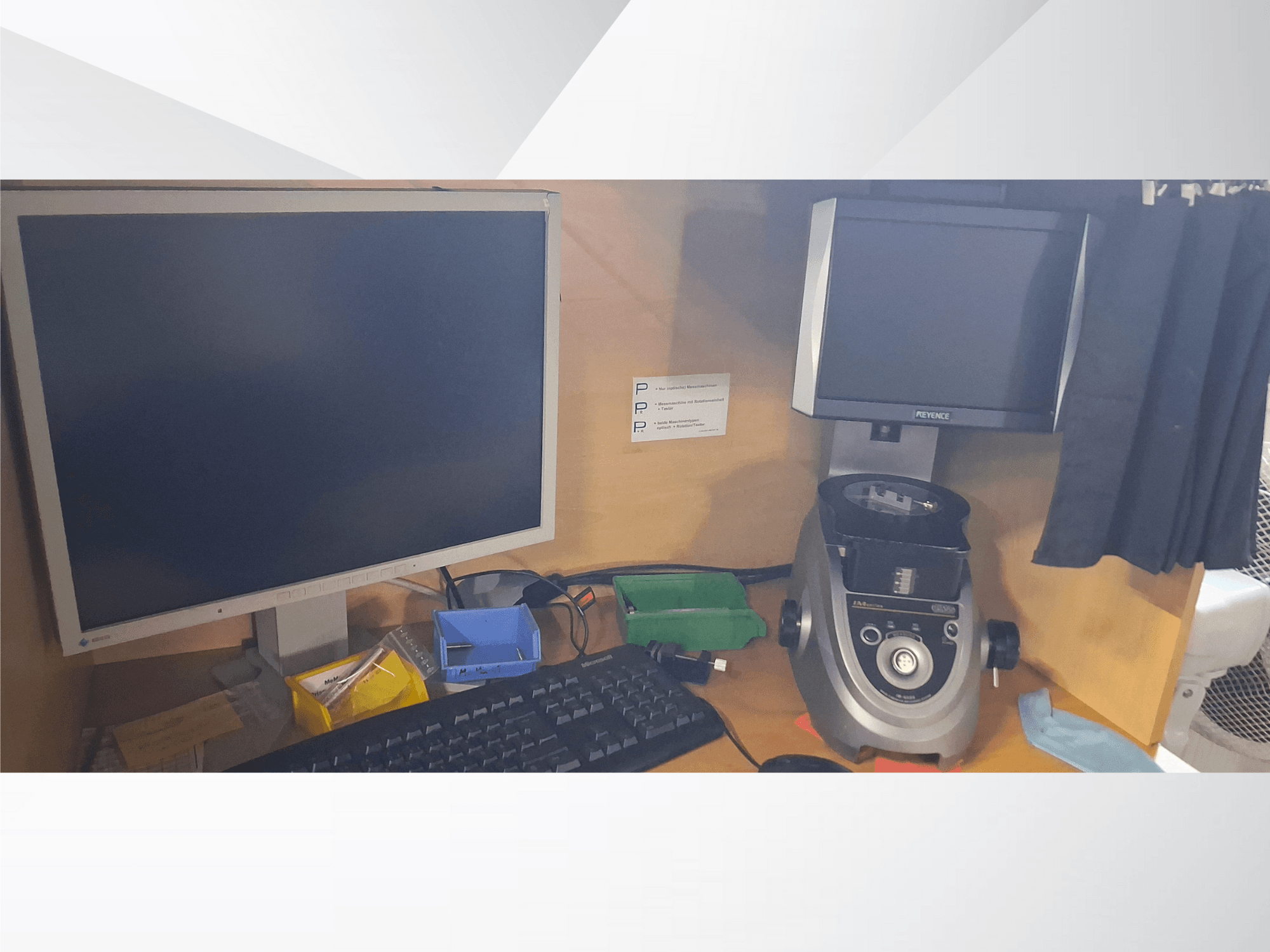 Computermonitor mit Tastatur, Display der Marke PEVA und ein graues Laborgerät auf einem Holztisch mit verschiedenen Ablagen und Papieren.