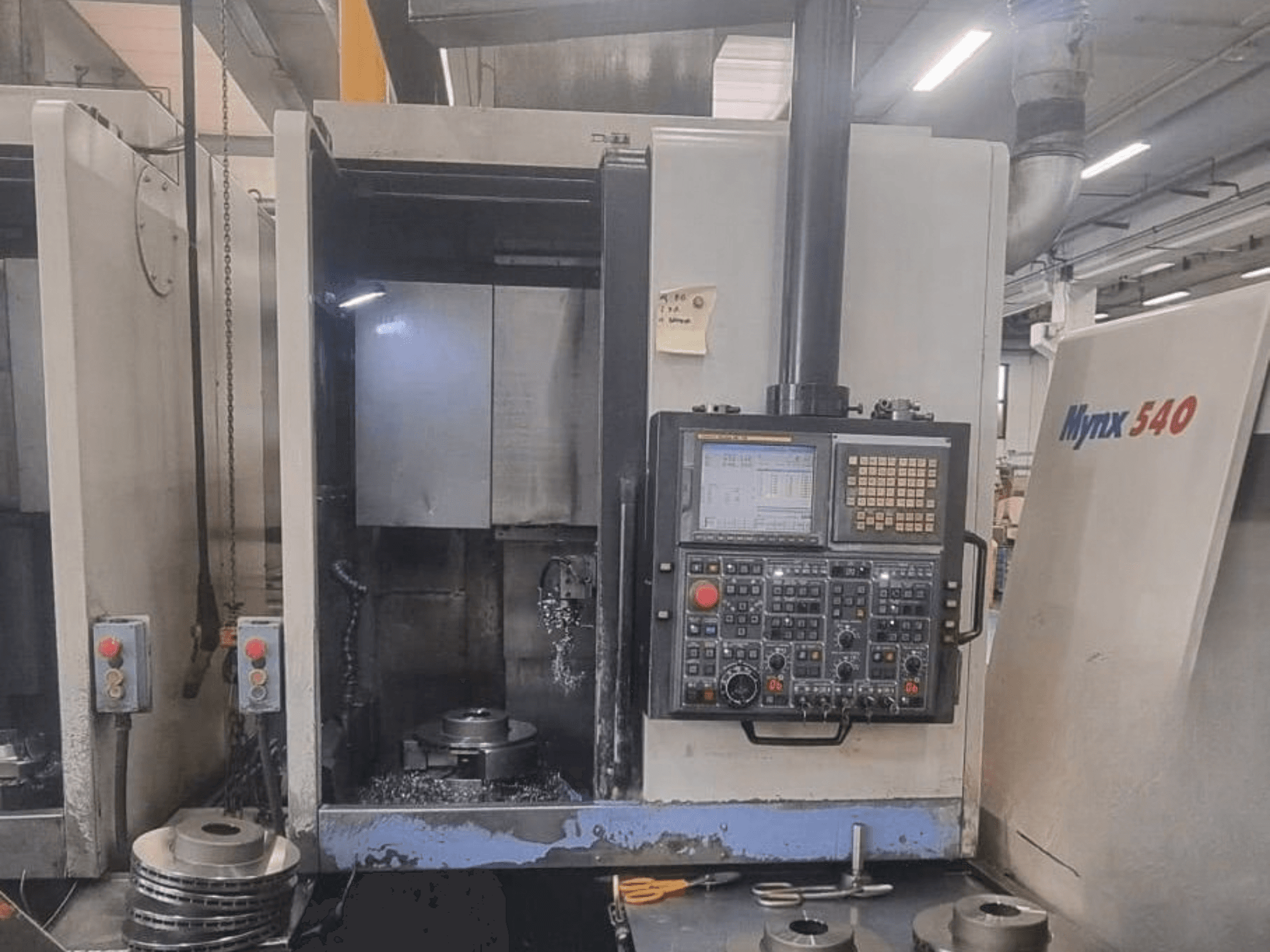 Vorderansicht einer vertikalen Drehmaschine vom Typ DOOSAN PUMA V400-2SP mit Blick auf das Bedienfeld und die Werkstückaufspannung im Inneren der Maschine.