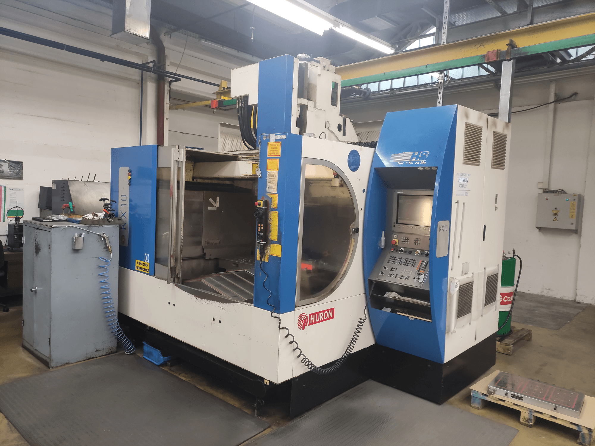 CNC-Maschine HURON KX10 in einer Werkstatt, Vorderansicht, mit Bedienfeld und großer Öffnung für die Bearbeitung.