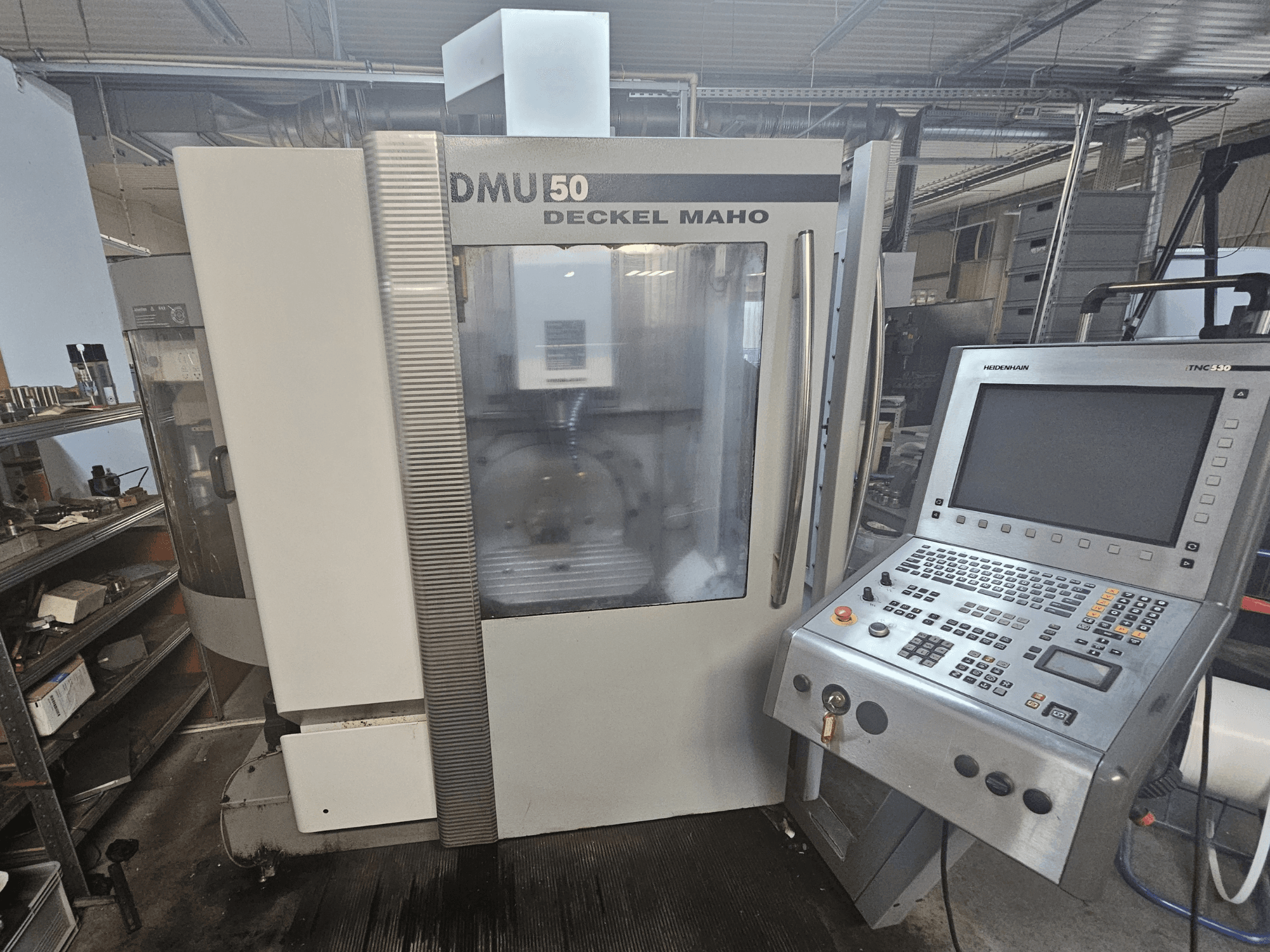 CNC-Maschine DMU 50 Deckel Maho, Vorderansicht mit sichtbarem Bedienfeld und Bedientasten, in einer Werkstattumgebung.