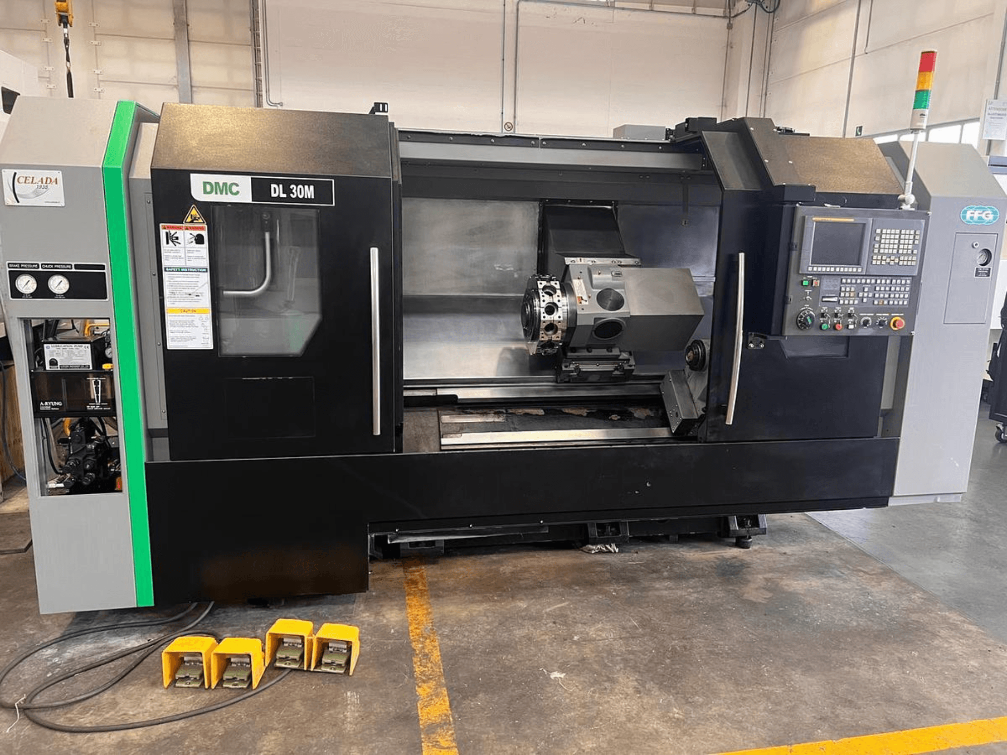 DMC DL 30M CNC-Maschine mit einer Seitenansicht, die die Bedienelemente, die Spindel und drei Fußpedale auf dem Boden zeigt.