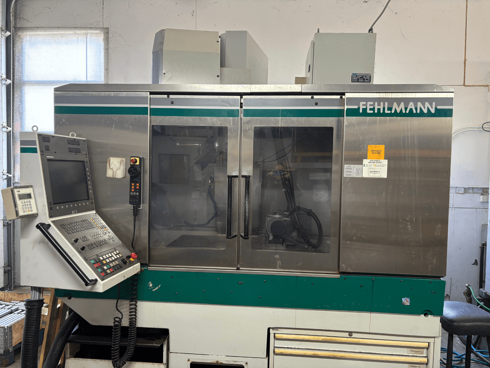 Vorderansicht des vertikalen Bearbeitungszentrums FEHLMANN Picomax 90-M mit Bedienfeld, durchsichtiger Verkleidung und Bedientasten.