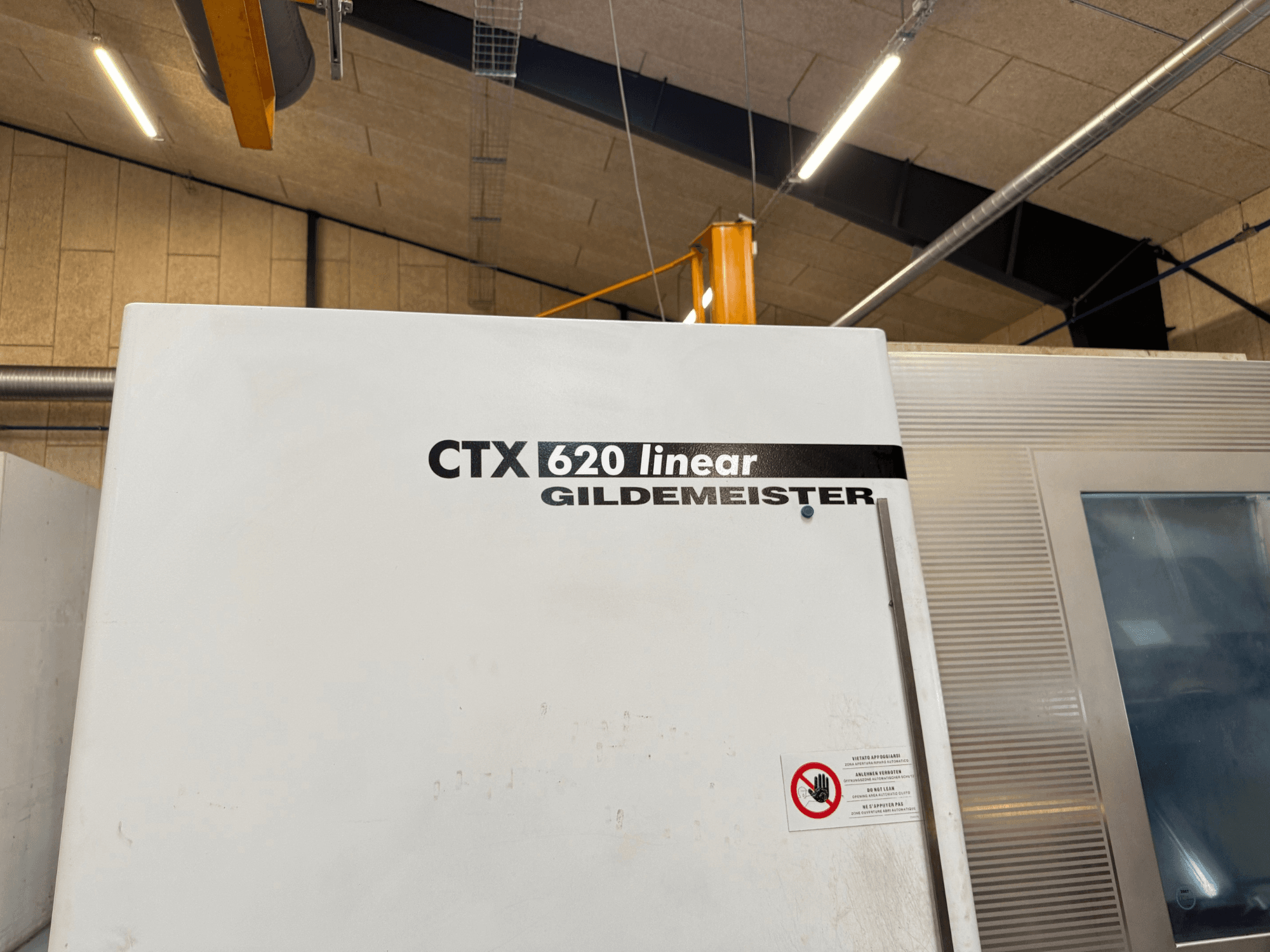 CTX 620 Linear Gildemeister Maschine in der Seitenansicht, mit weißem Äußeren und Sicherheitswarnschildern.