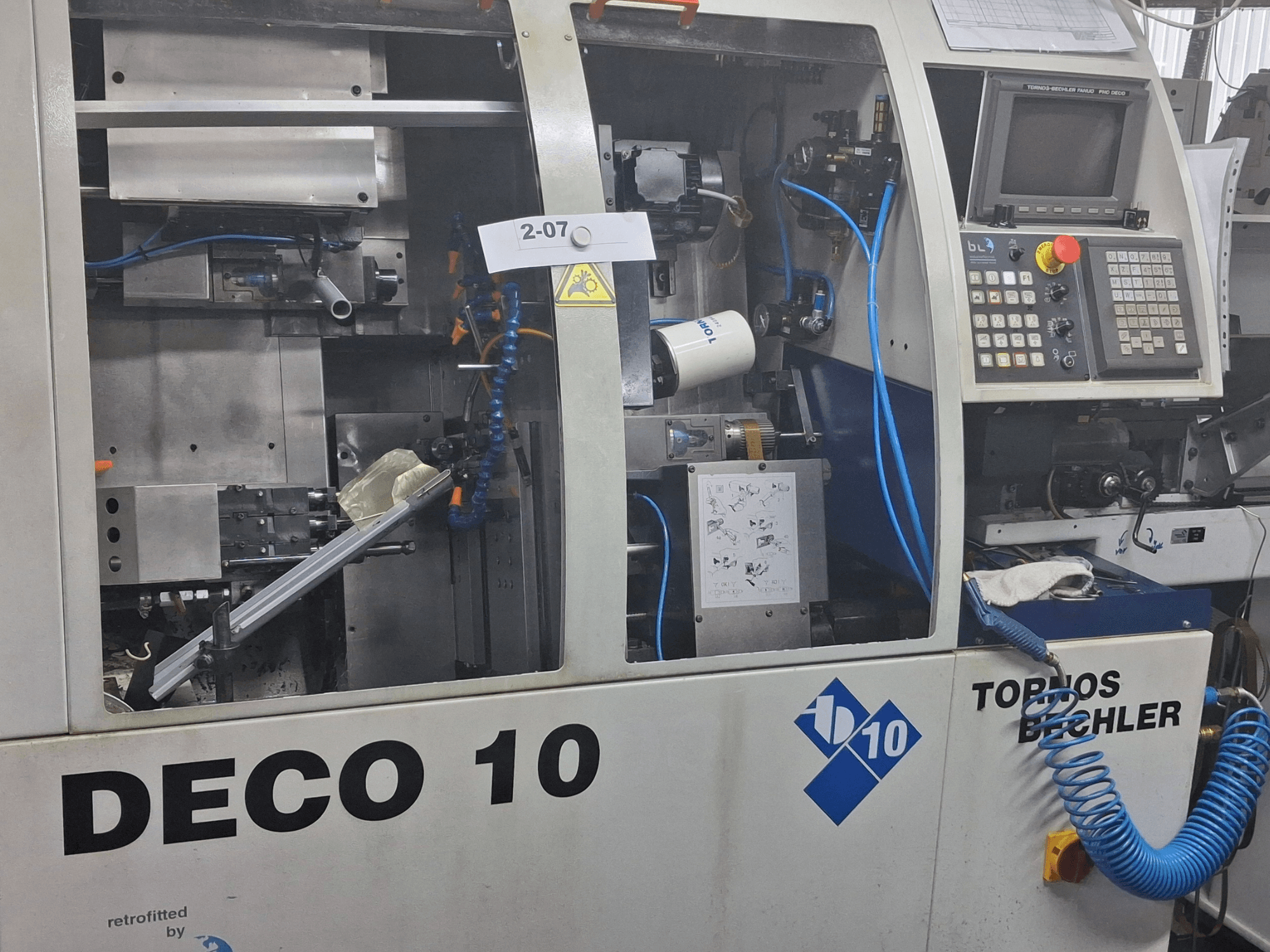 Nahaufnahme der Schweizer Drehmaschine TORNOS Deco 10a mit Details des Innenlebens und des Bedienfeldes.