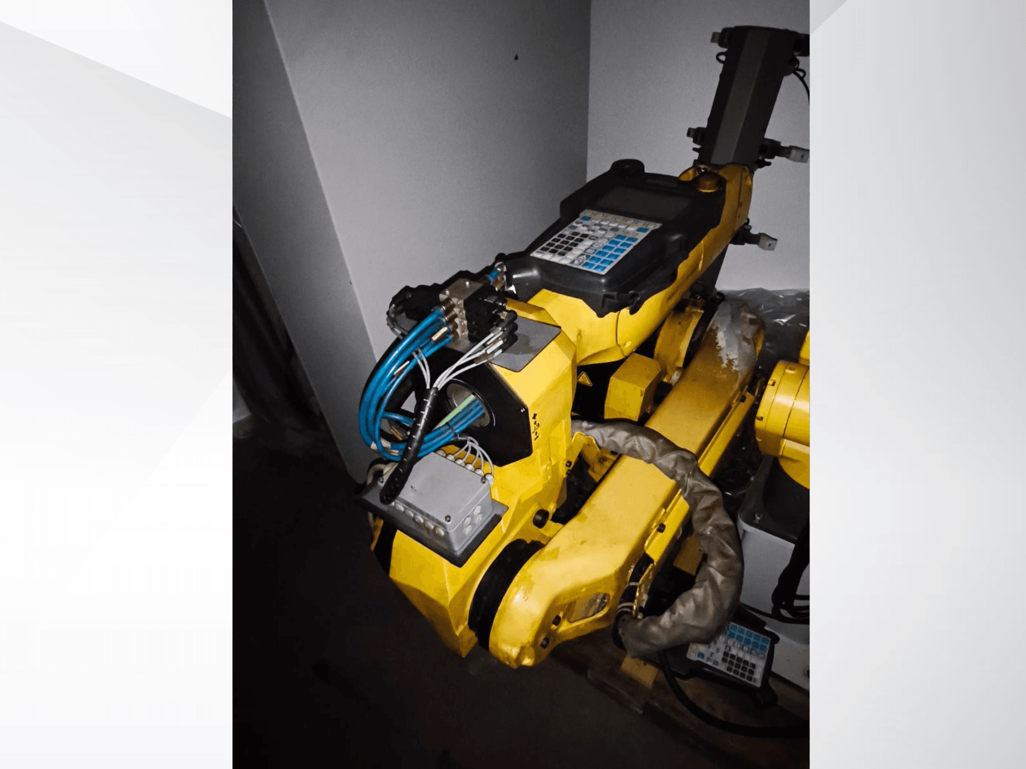 FANUC M-20iA Roboterarm in einer Seitenansicht, mit gelbem Gehäuse, Bedienfeld und angeschlossener Verkabelung.