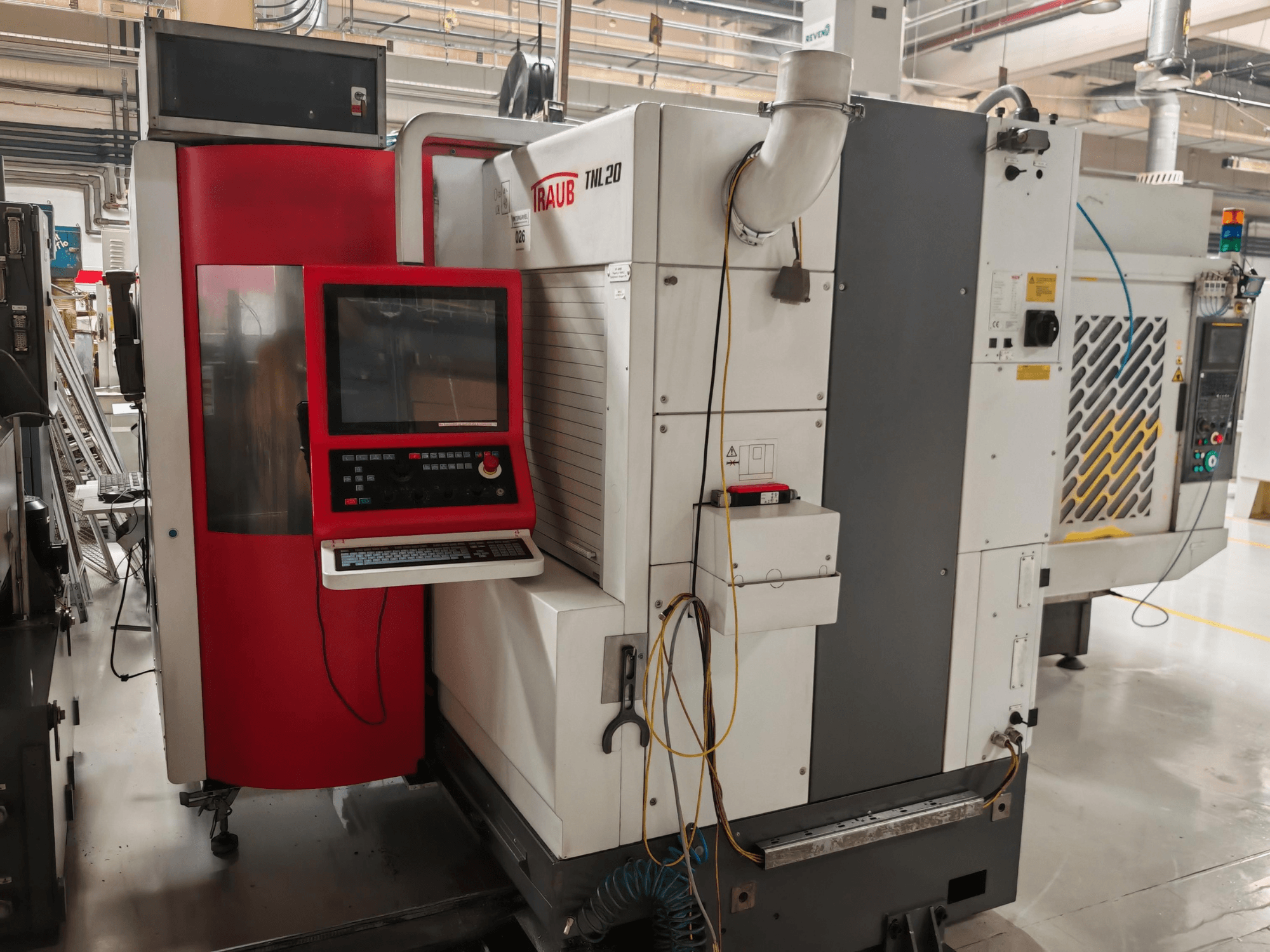 TRAUB TLN20 Drehmaschine nach Schweizer Art, Vorderansicht mit Bedienfeld, rotem Gehäuse und industriellen Details.