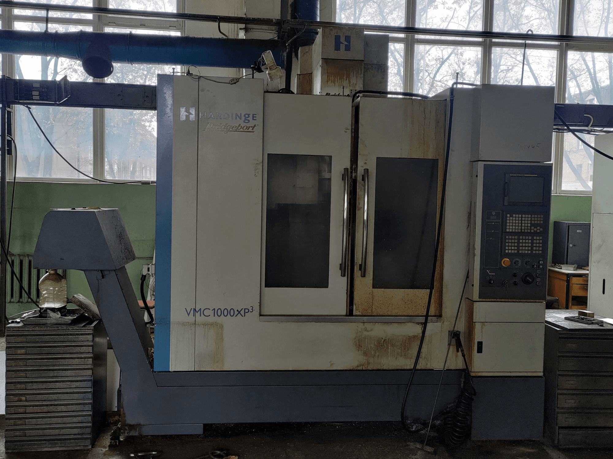 Vertikales Bearbeitungszentrum Bridgeport VMC1000 XP3 in der Vorderansicht, mit sichtbarem Bedienfeld und leichten Gebrauchsspuren.