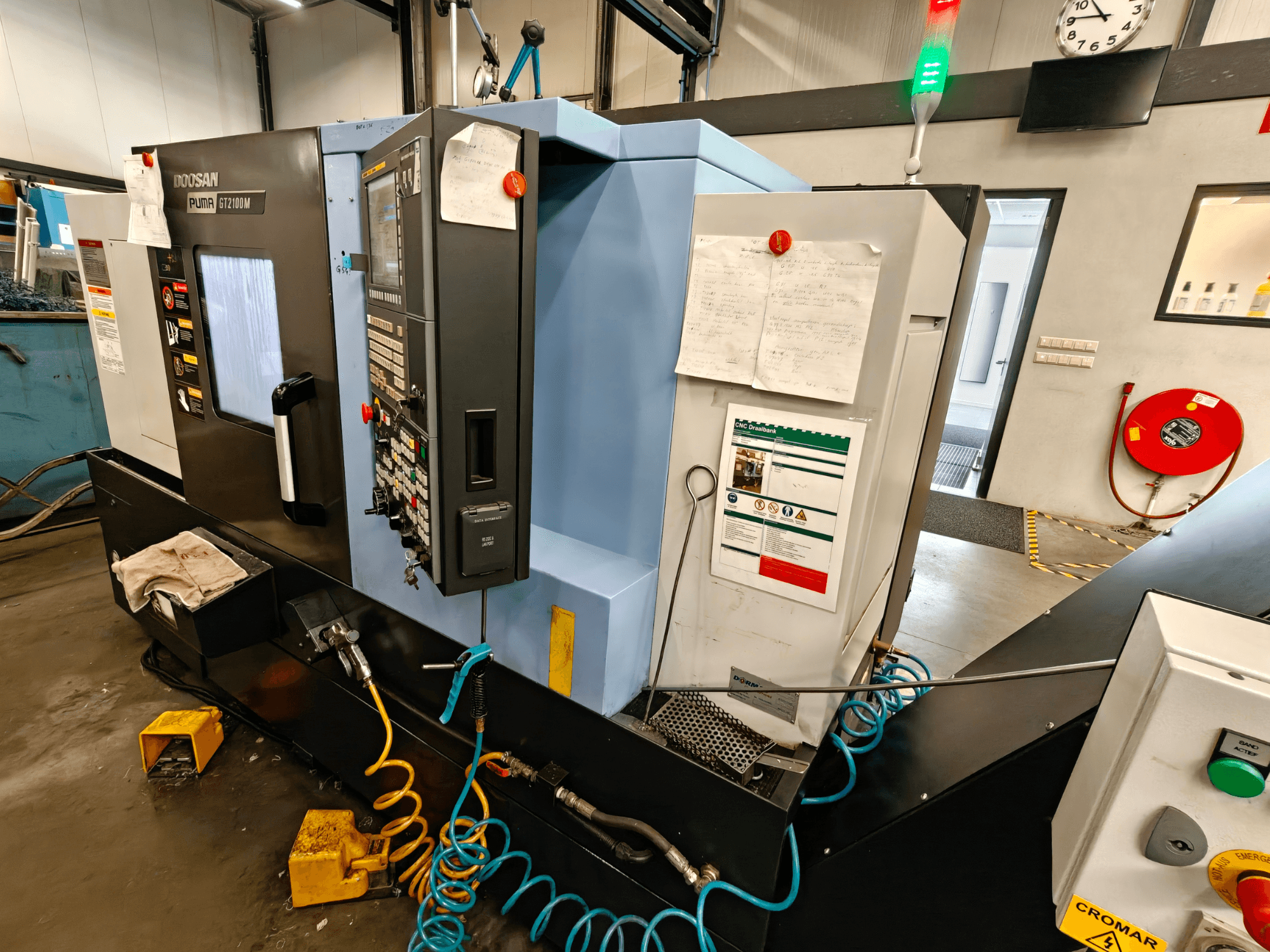 Frontansicht der horizontalen Drehmaschine DOOSAN Puma GT 2100M mit Bedienfeld, Sicherheitseinrichtungen und Wartungshinweisen.