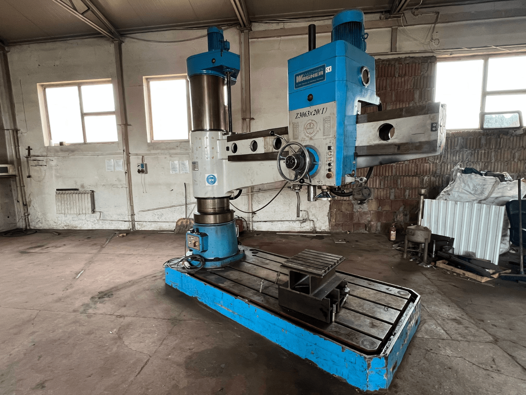 Wagner Z3063x210 Bohrmaschine in einer Werkstatt, Vorderansicht; blau-silbernes Design mit Metallfuß und Arbeitstisch.