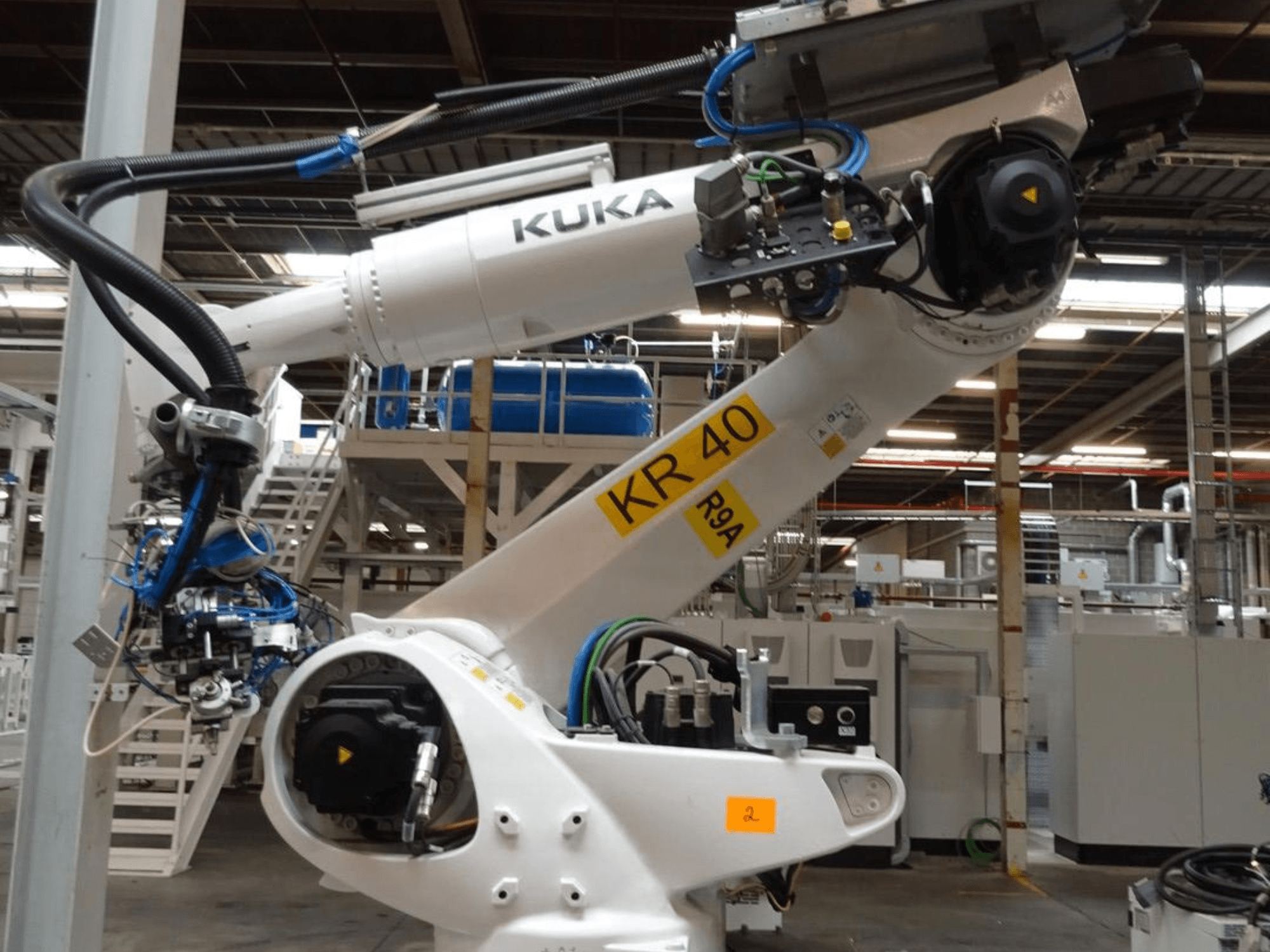 KUKA Roboterarm KR 120 R3100-2 in der Seitenansicht mit Bedienfeld und mechanischen Komponenten in einer industriellen Umgebung.