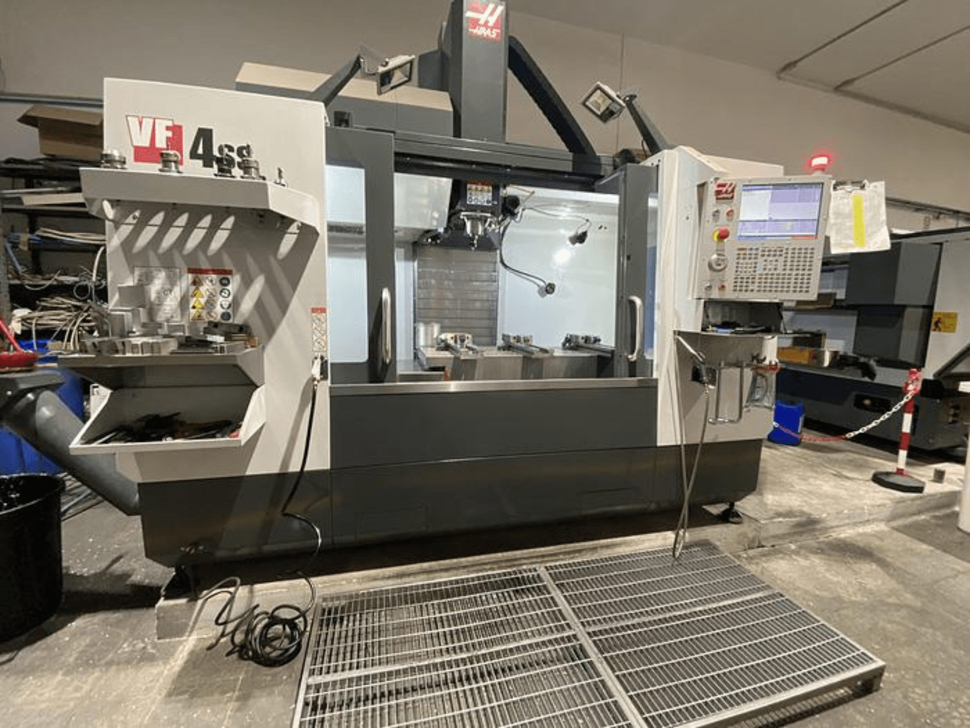 Haas VF-4SS CNC-Fräsmaschine, Vorderansicht, mit Werkzeugablage, Bedienfeld und sichtbarem Arbeitsbereich in einer Werkstattumgebung.