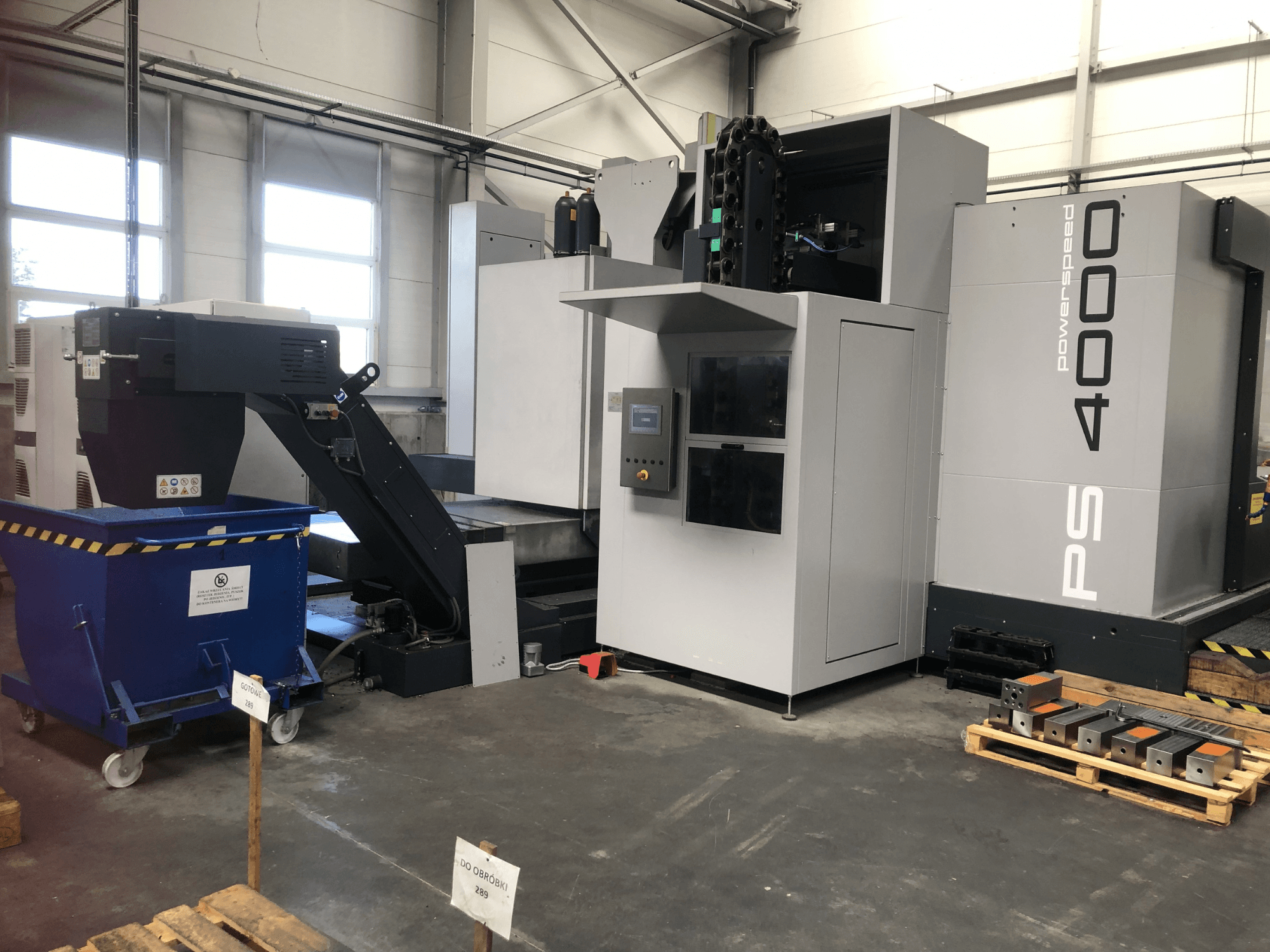 Das horizontale Bearbeitungszentrum SHW PowerSpeed 4000 in einer Fabrikumgebung, mit Blick auf das Bedienpult, das Förderband und die Werkstücke.