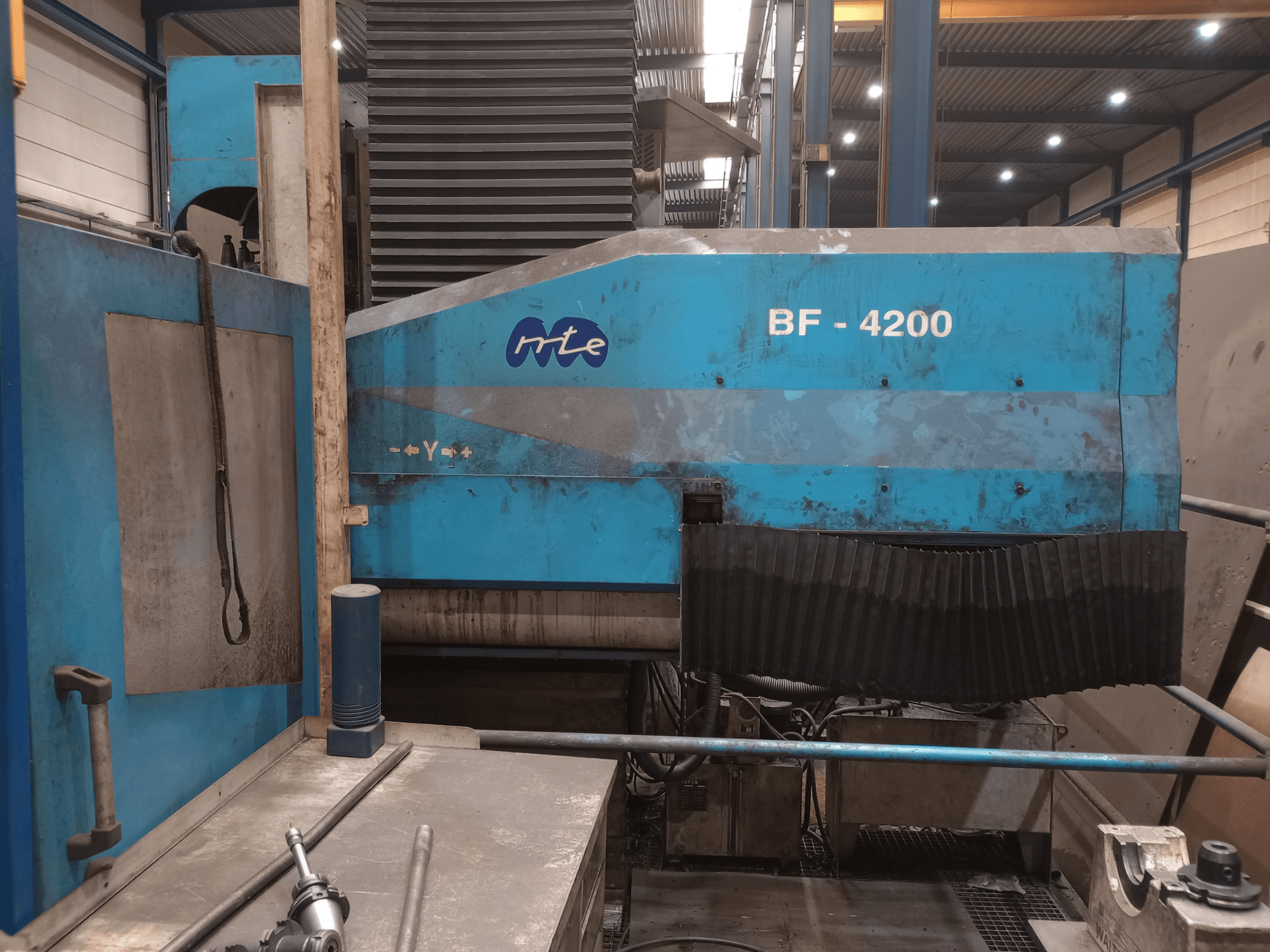 Fräsmaschine vom Typ MTE BF 4200 in Bettbauweise, Seitenansicht, mit blauer Außenverkleidung und detailliert dargestellten Maschinenkomponenten in einer Werkstattumgebung.