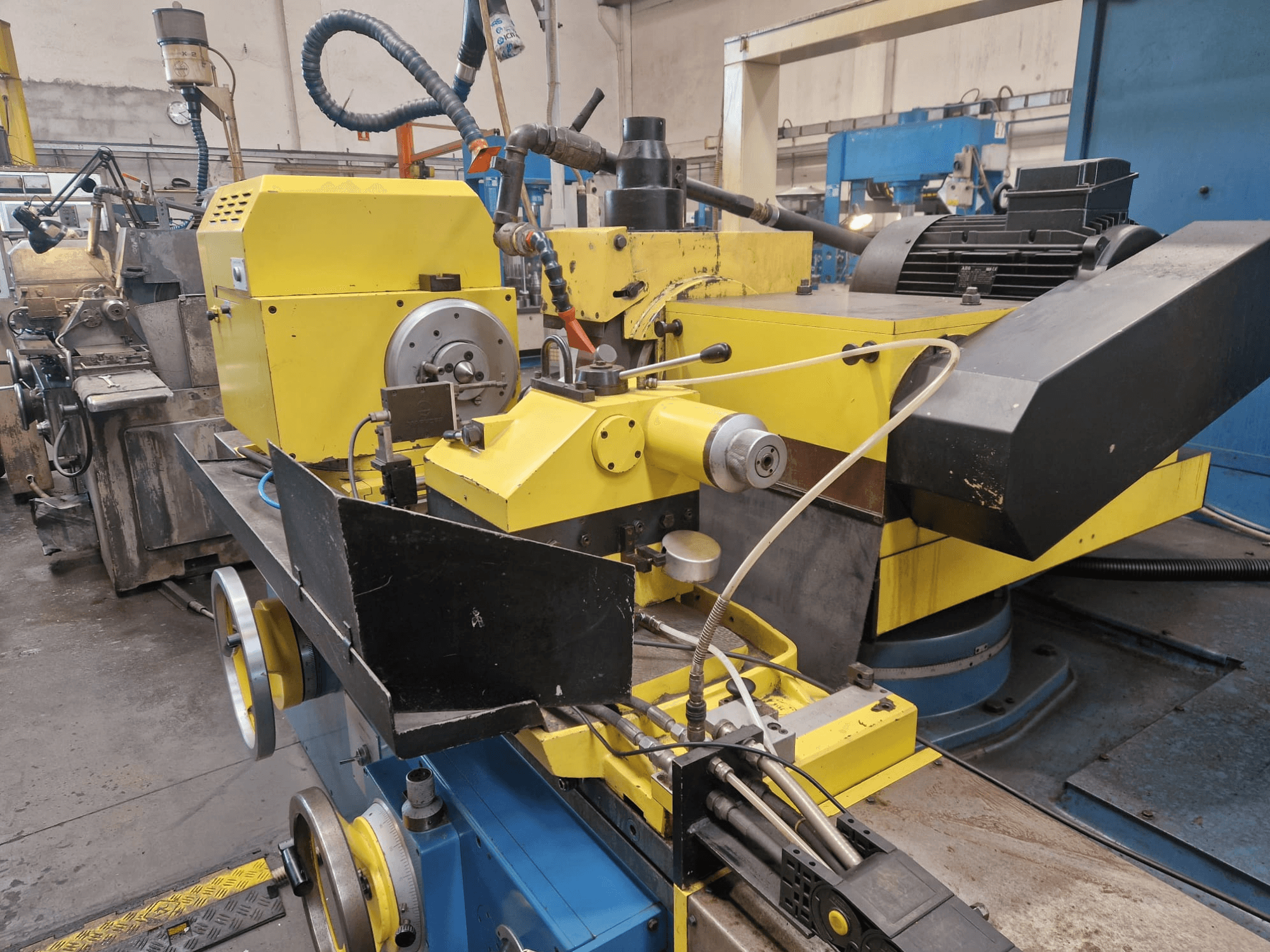 Gelbe Industriemaschine mit schwarzem Teil, mit Zifferblatt und Schläuchen, leicht schräg von vorne gesehen.