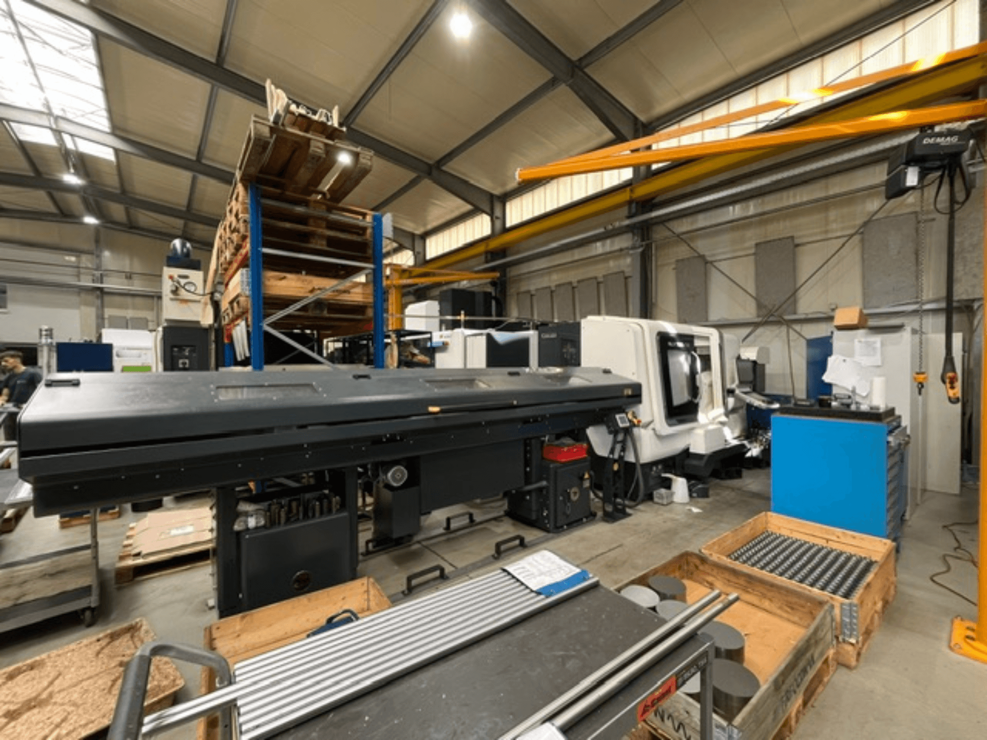 Horizontaldrehmaschine DMG MORI MORI NLX 2500/700 SY in einer Fabrikumgebung, von der Seite gesehen, mit sichtbaren Werkzeugen und Paletten.