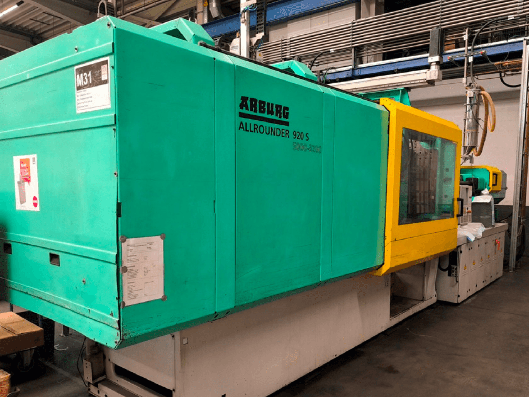Arburg Allrounder 920 S Spritzgießmaschine in aquablau und gelb, Seitenansicht mit Bedienfeld und Komponenten.