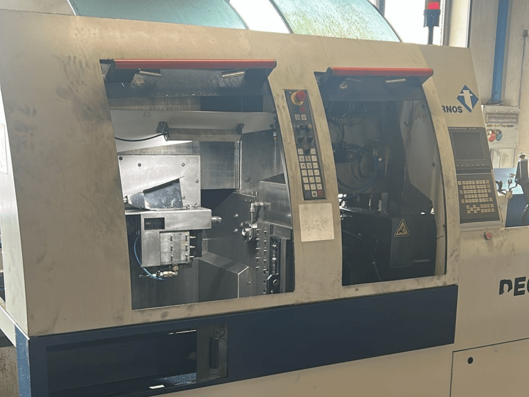 Alt-Text: Vorderansicht der TORNOS Deco 13 b Schweizer Drehmaschine mit Bedienfeldern und internen Komponenten.