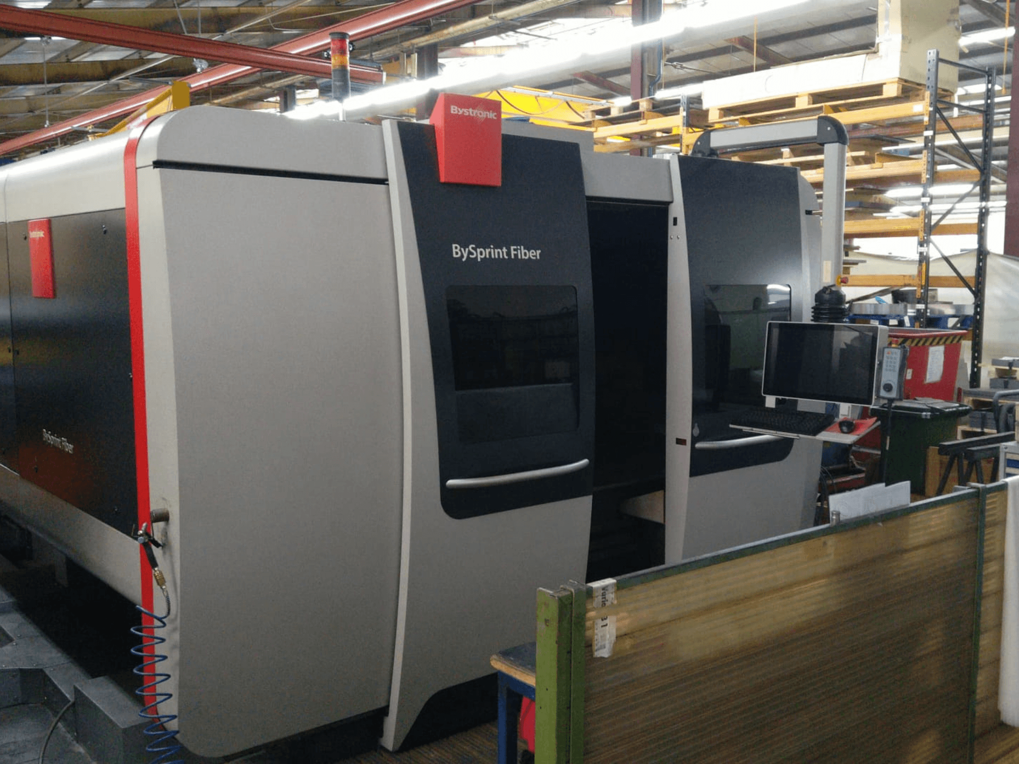 Bystronic BySprint Faserlaserschneider, Frontansicht mit Bedienfeld, sichtbare Details sind zwei Türen und ein Monitor an der Seite.