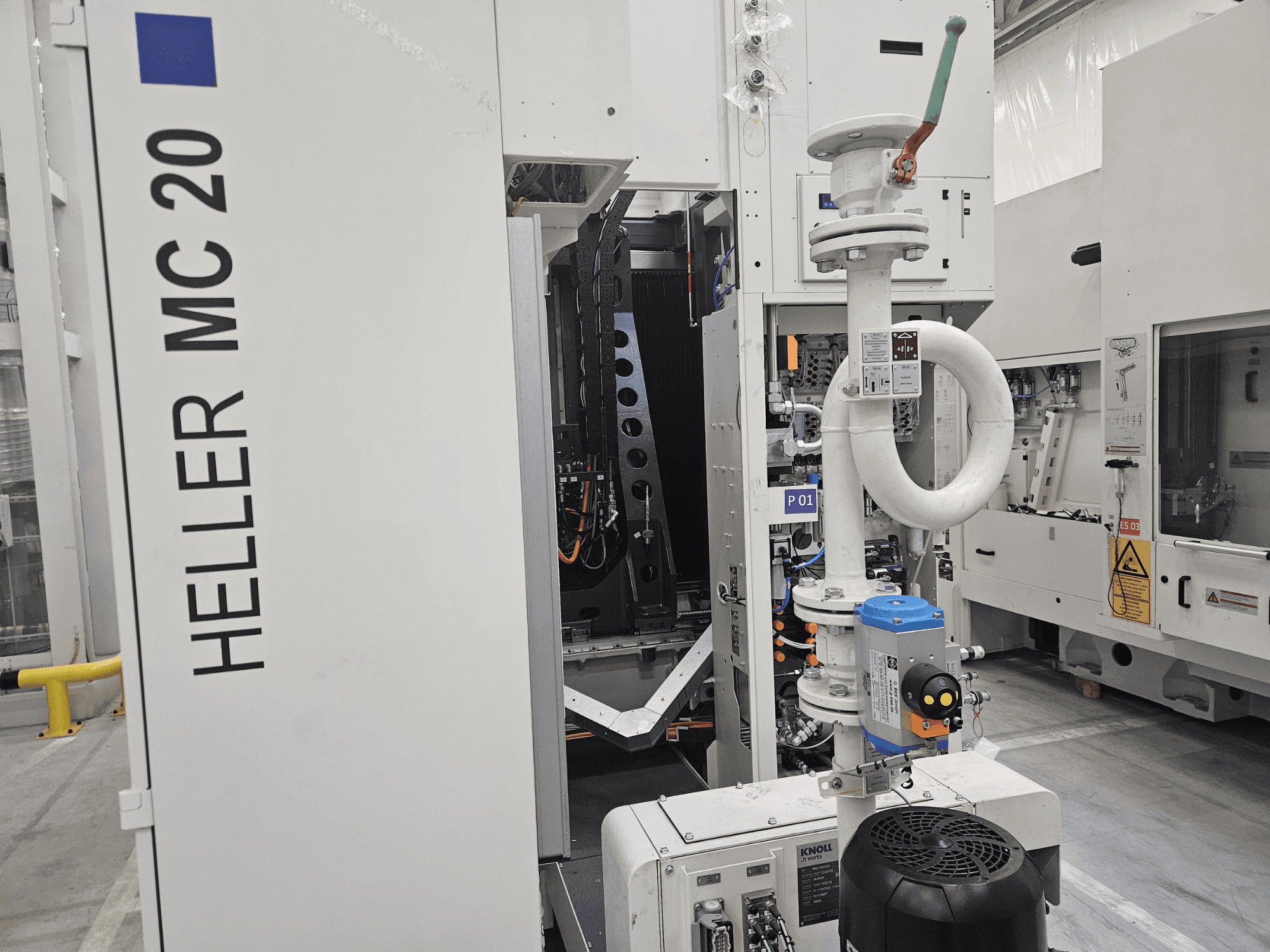 Heller MC 20 Maschine in einer Werksumgebung, die das Bedienfeld und die mechanischen Komponenten in der Seitenansicht zeigt.