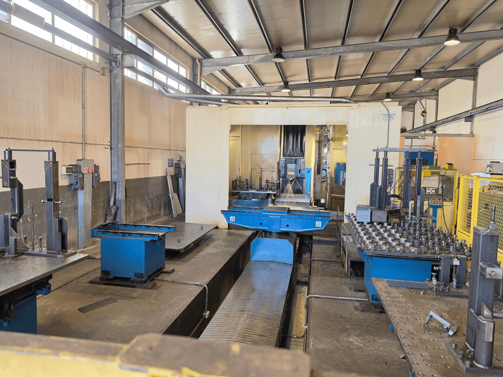 Das horizontale Bearbeitungszentrum Mandelli RS1500U in einer Fabrikumgebung, in der Maschinen, Werkzeuge und Arbeitsflächen zu sehen sind.