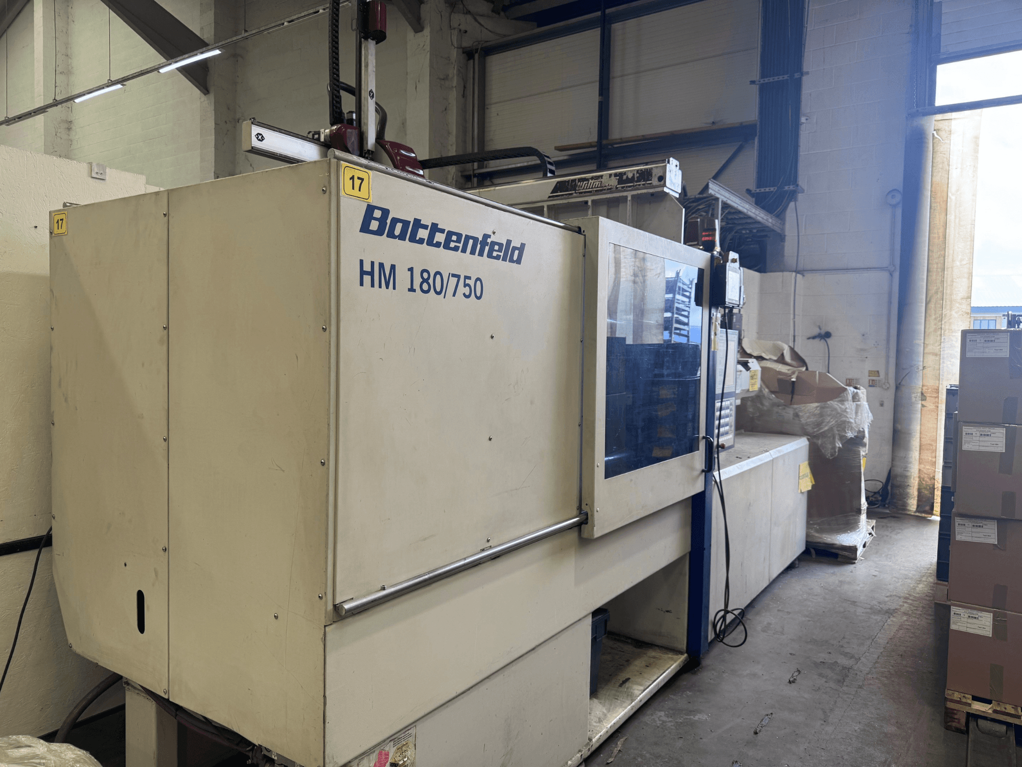 Die hydraulische Spritzgießmaschine HM150750 von Battenfeld in der Frontalansicht, die das Bedienfeld und die Umgebung zeigt.