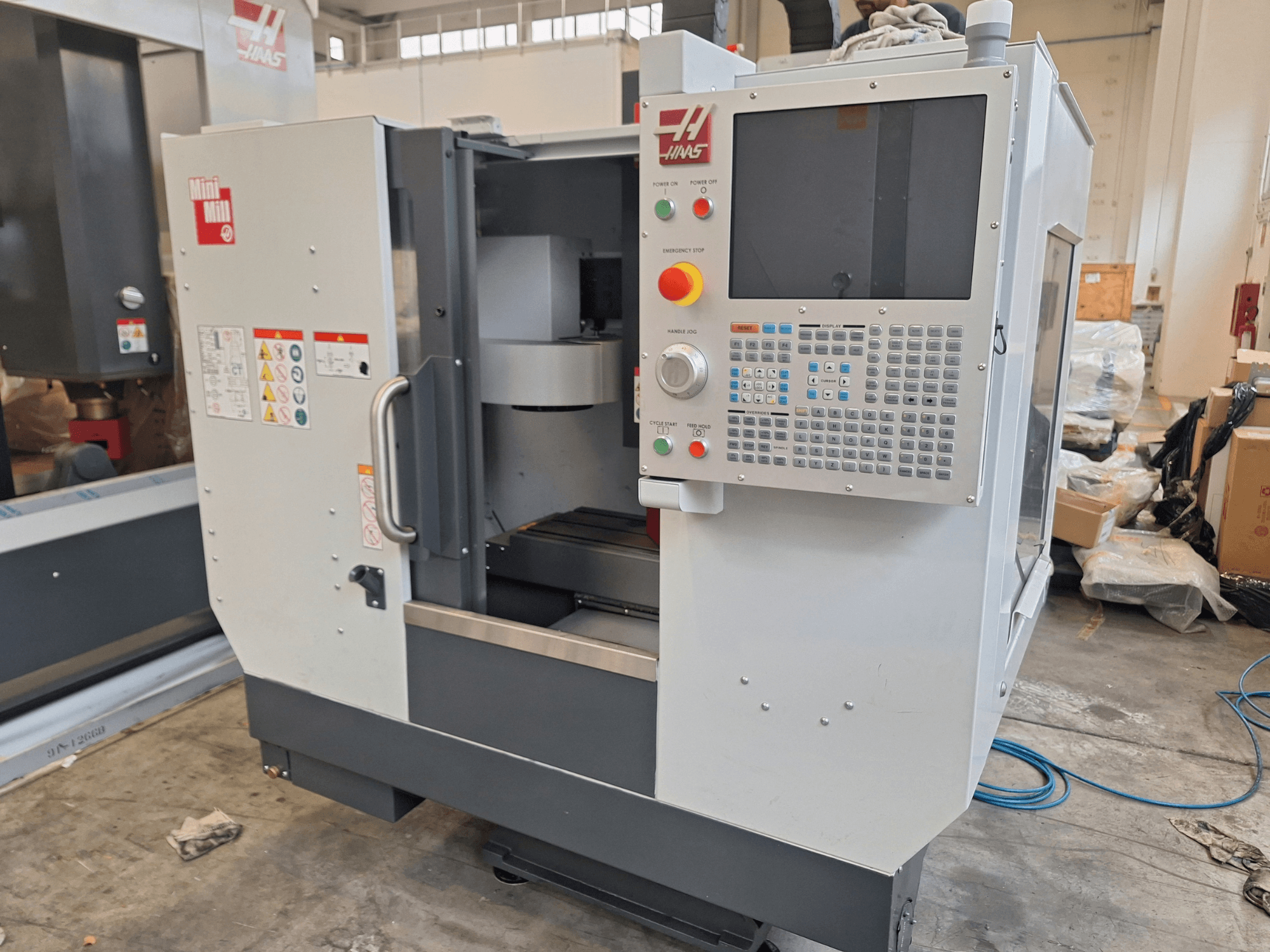 Vertikales Bearbeitungszentrum „HAAS Mini Mill“ in der Vorderansicht, mit einem Bedienfeld mit Tasten und einem Bildschirm.