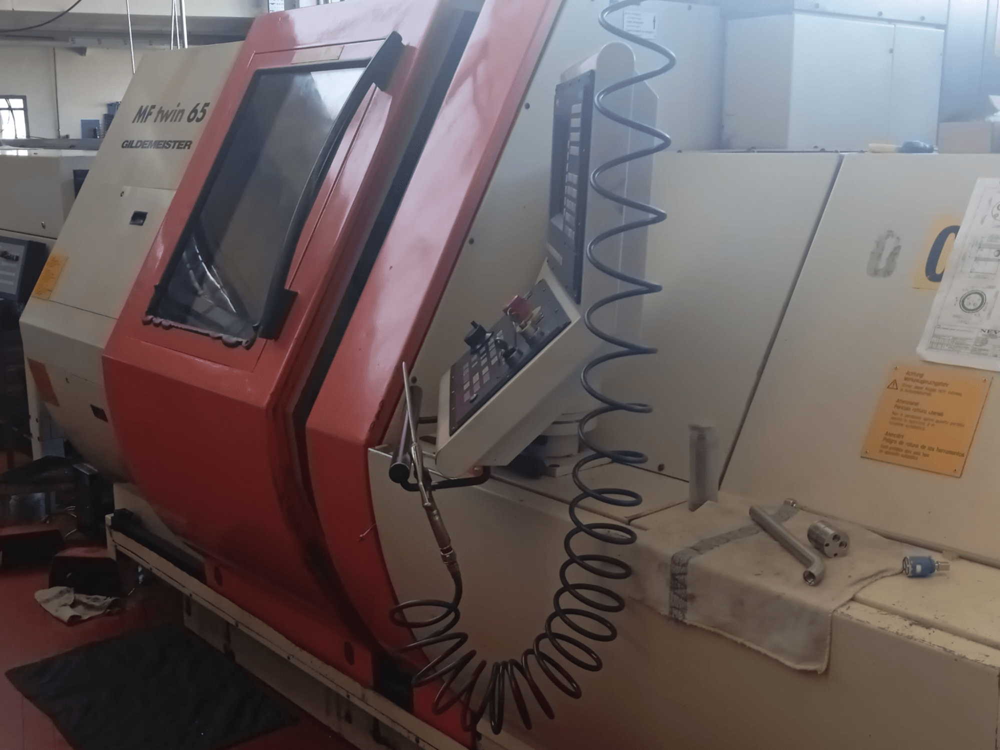 Orange-weiße MF twin 65 Gliedemeister-Maschine, Vorderansicht, mit Bedienfeld und Werkzeugen auf einem Tuch.