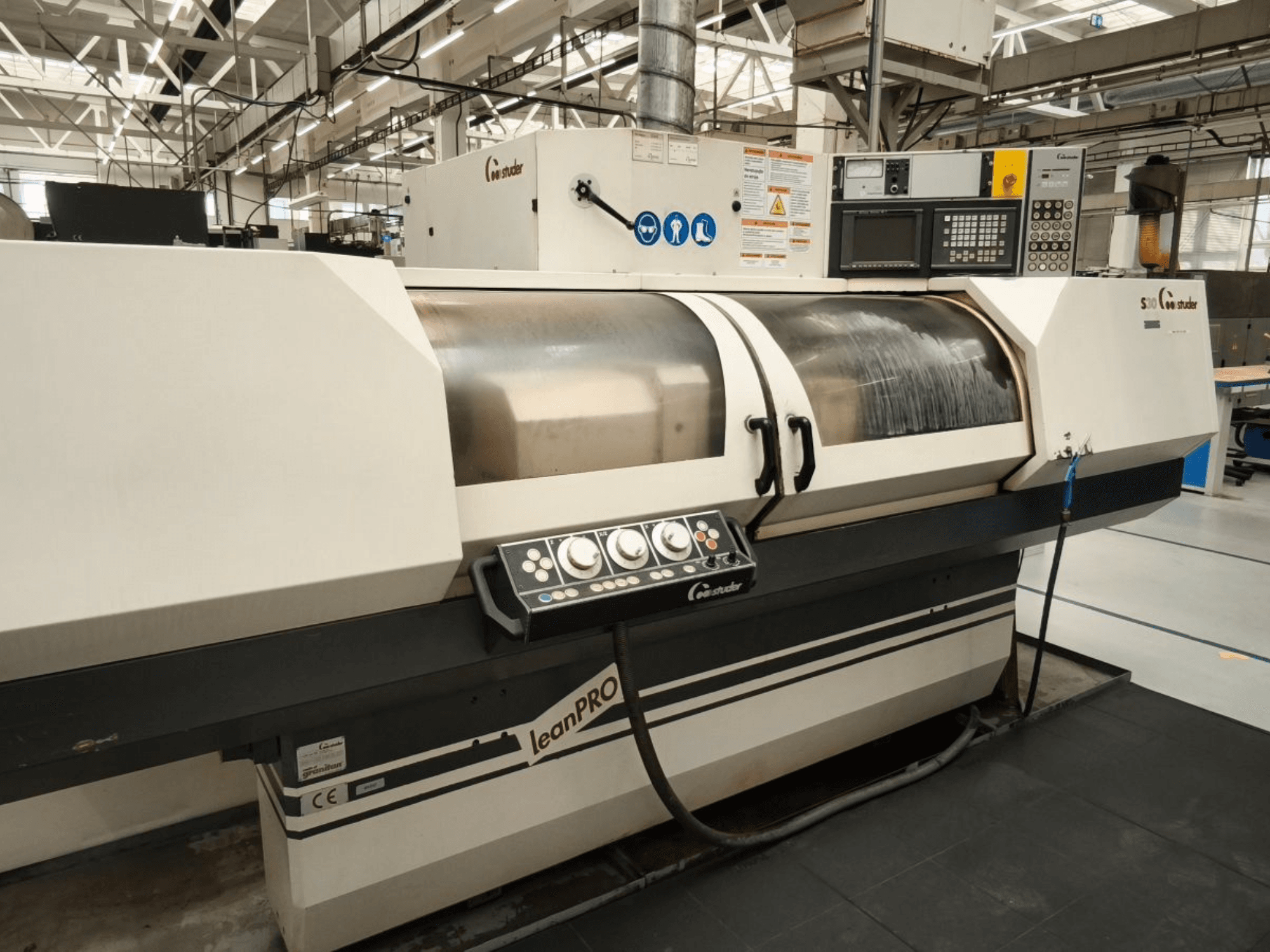 STUDER S30 LEAN PRO Rundschleifmaschine, Seitenansicht, mit Bedienfeld und Schleifscheibenabdeckung in einer industriellen Umgebung.