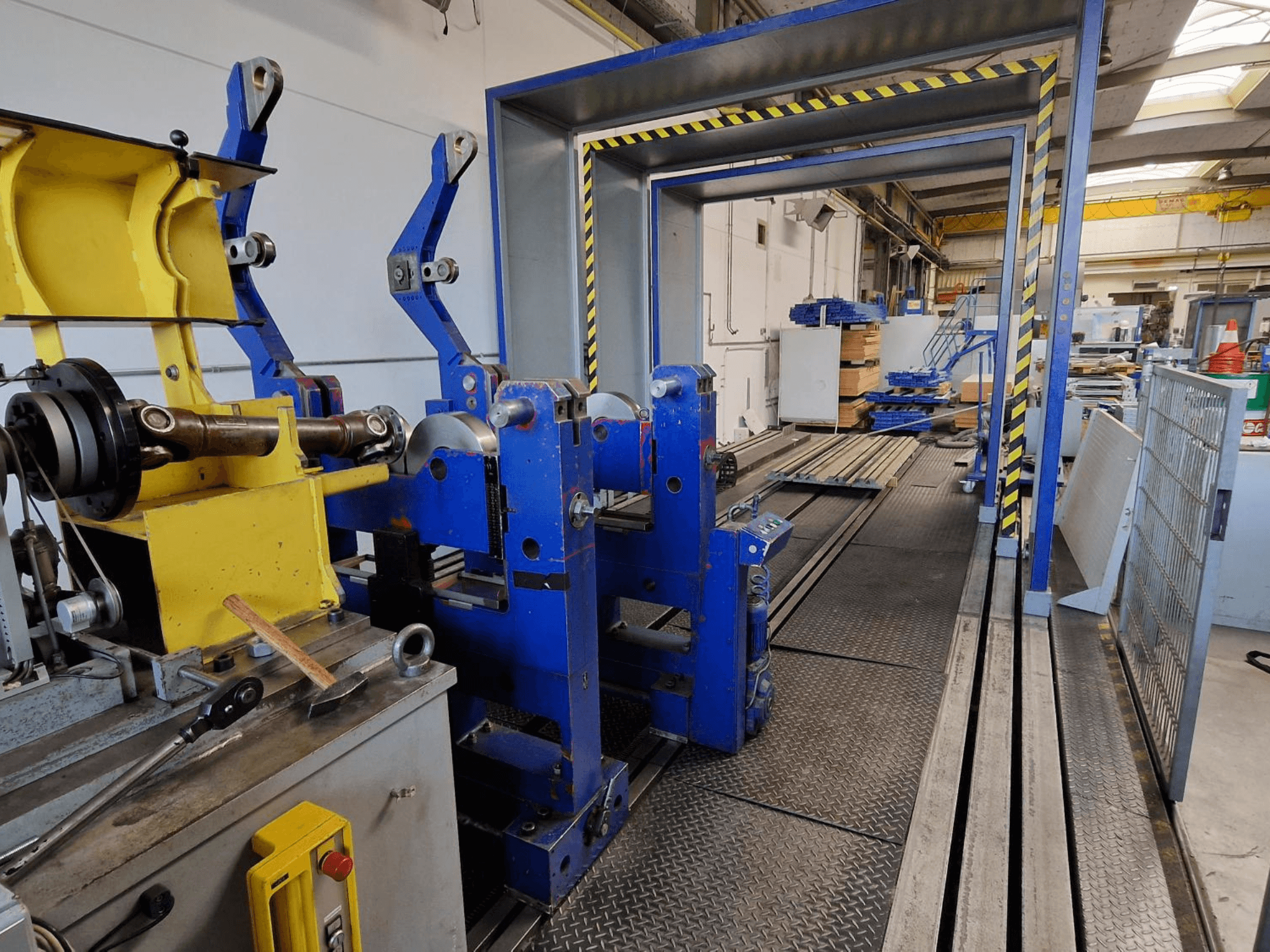 Werkzeugmaschine SCHENCK HM 70U BU, Seitenansicht, die die blaue Konstruktion mit gelben Bauteilen und das Bedienfeld in einer industriellen Umgebung zeigt.