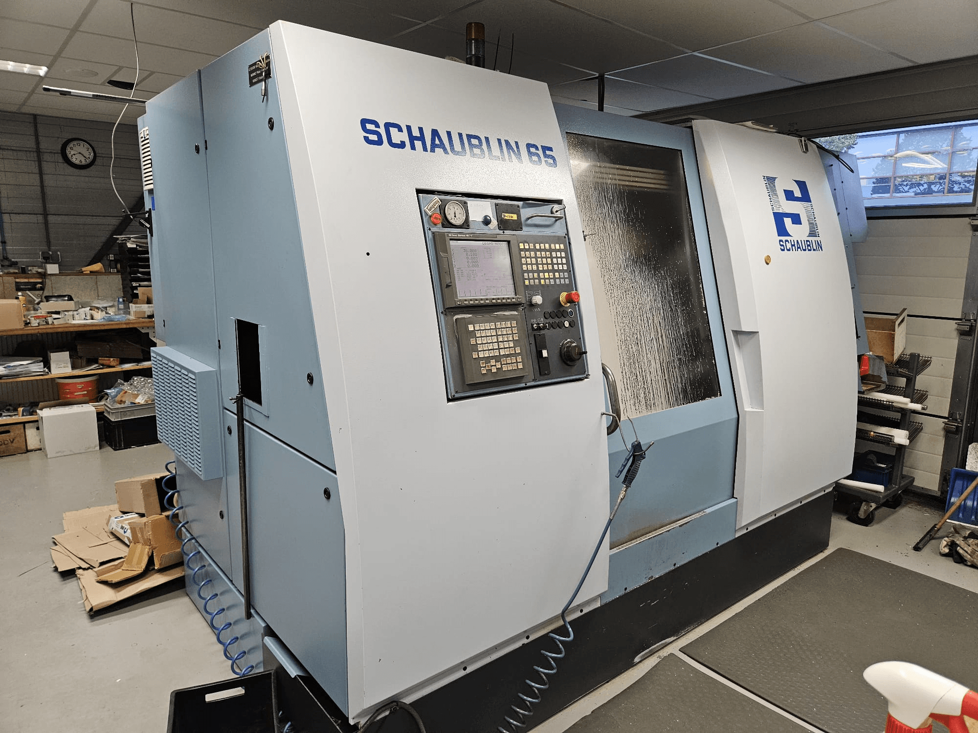 SCHAUBLIN 65 CNC-Maschine, Seitenansicht, mit Bedienfeld, blau-grauem Gehäuse und sichtbarem Kühlsystem.