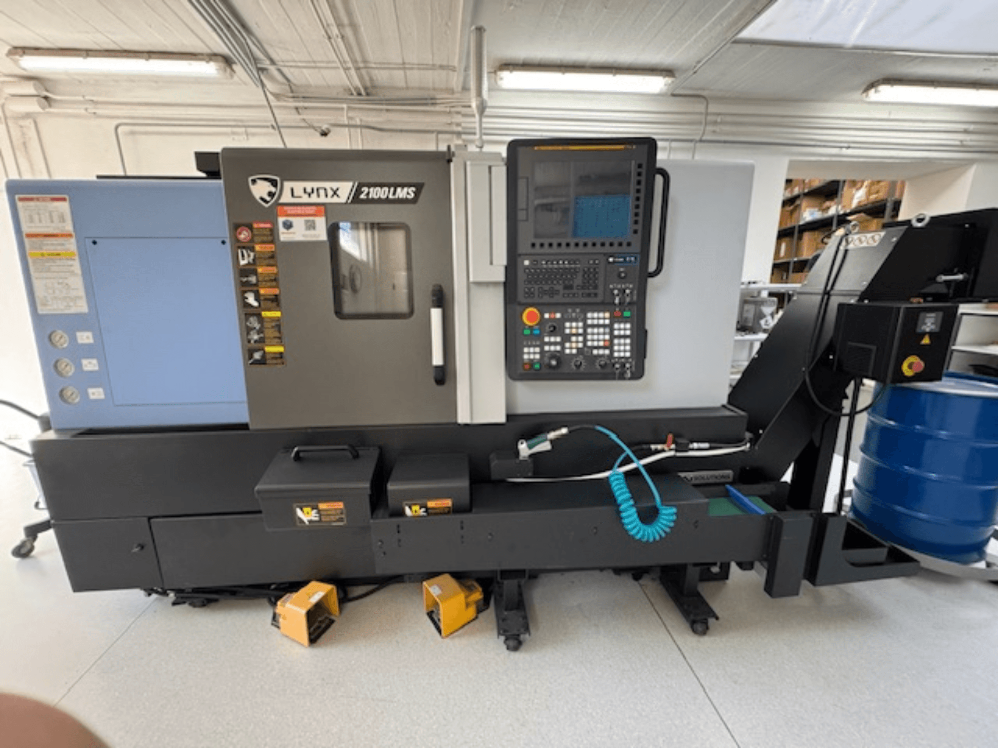 DOOSAN LYNX 2100LMSA Horizontaldrehmaschine, Vorderansicht, mit Bedienfeld, Kühlmittelschlauch und Aufbewahrungsboxen.
