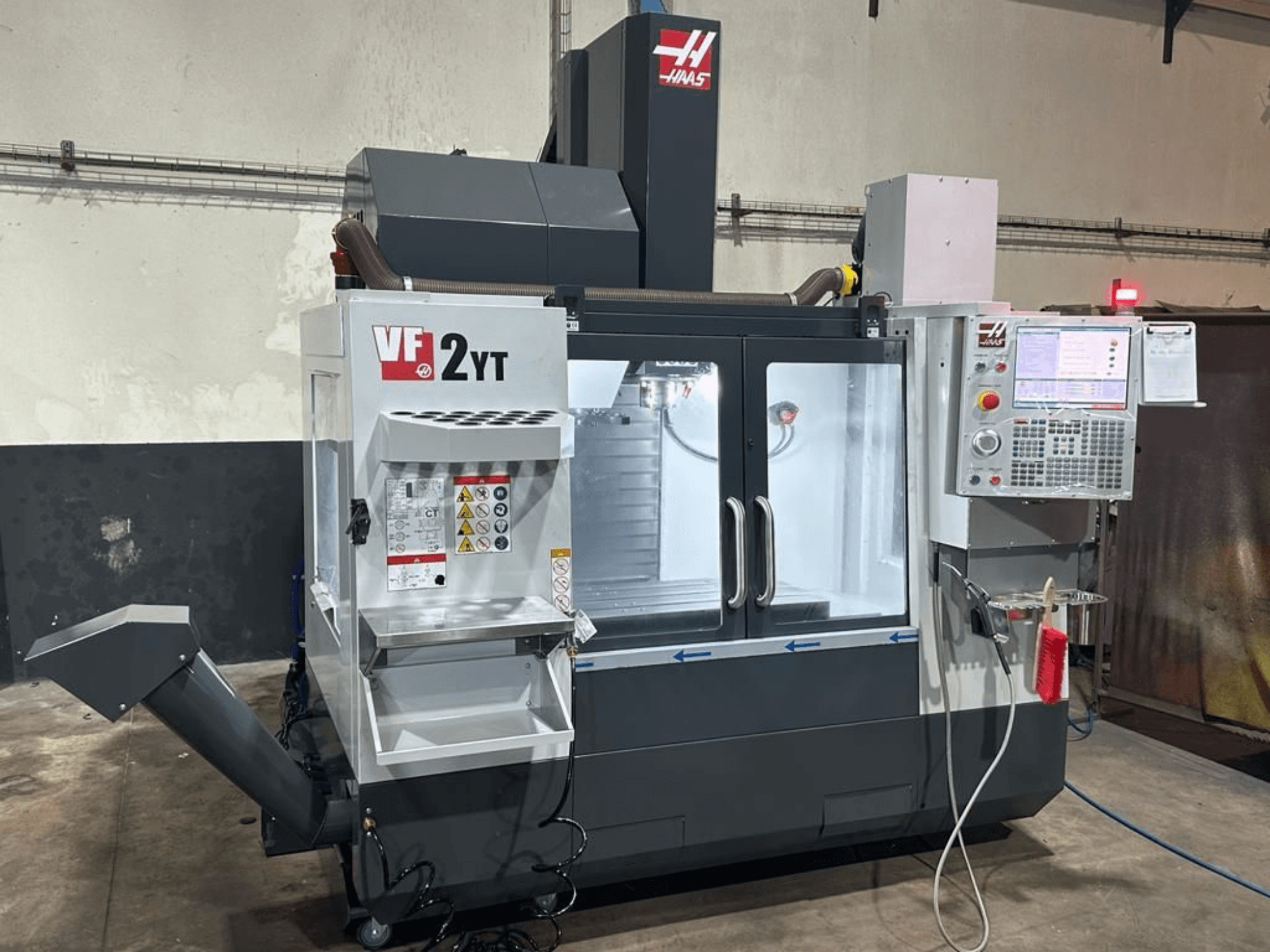 Vertikales Bearbeitungszentrum HAAS VF-2YT-EU in der Vorderansicht, mit Blick auf das Bedienfeld und das Werkzeugmagazin.