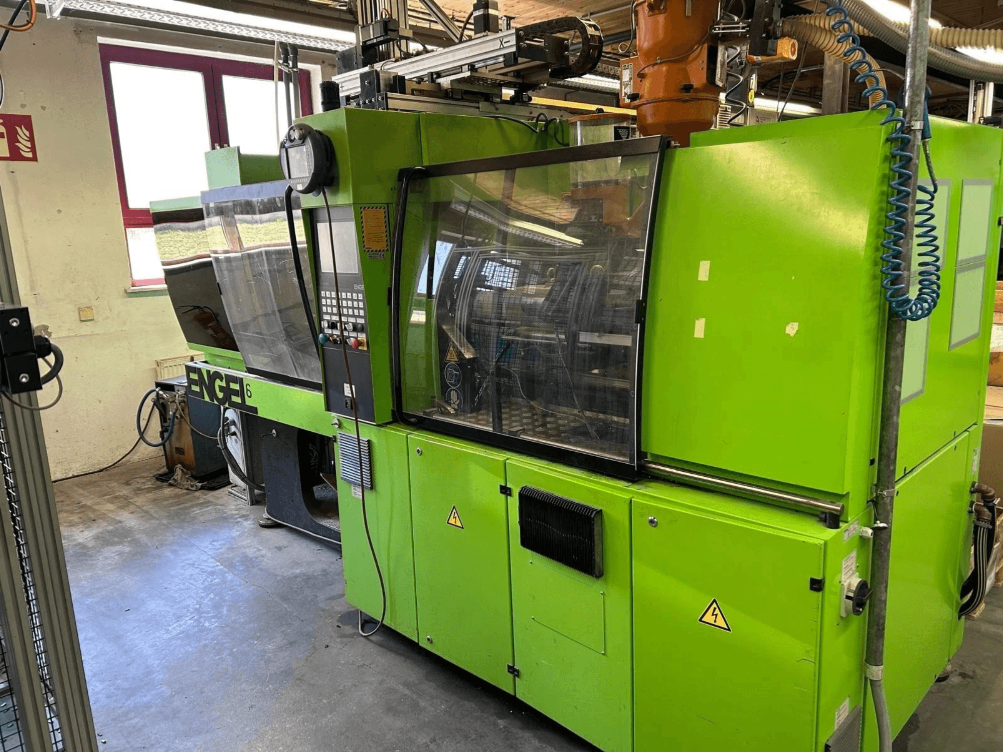 Vorderansicht der hydraulischen Spritzgießmaschine Engel VICTORY 330/80 Tech mit grüner Außenverkleidung und Bedienfeld.